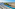 Resort infinity pool with sun loungers, palm trees, arid coast, and ocean.