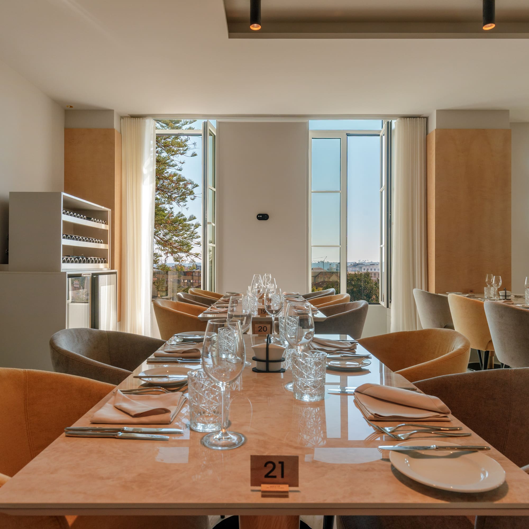 Elegant restaurant dining room, set tables, plush chairs, city view.
