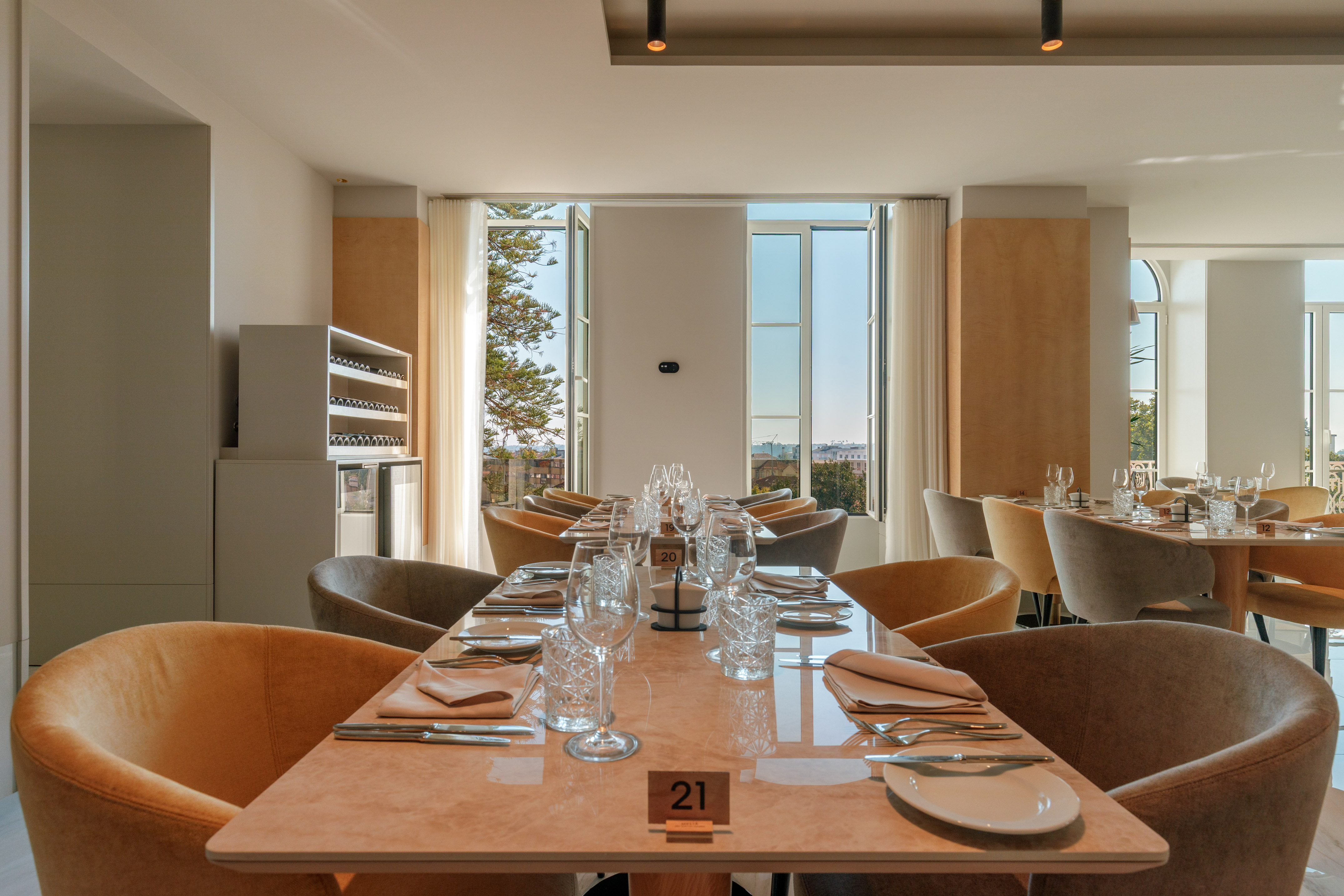 Elegant restaurant dining room, set tables, plush chairs, city view.