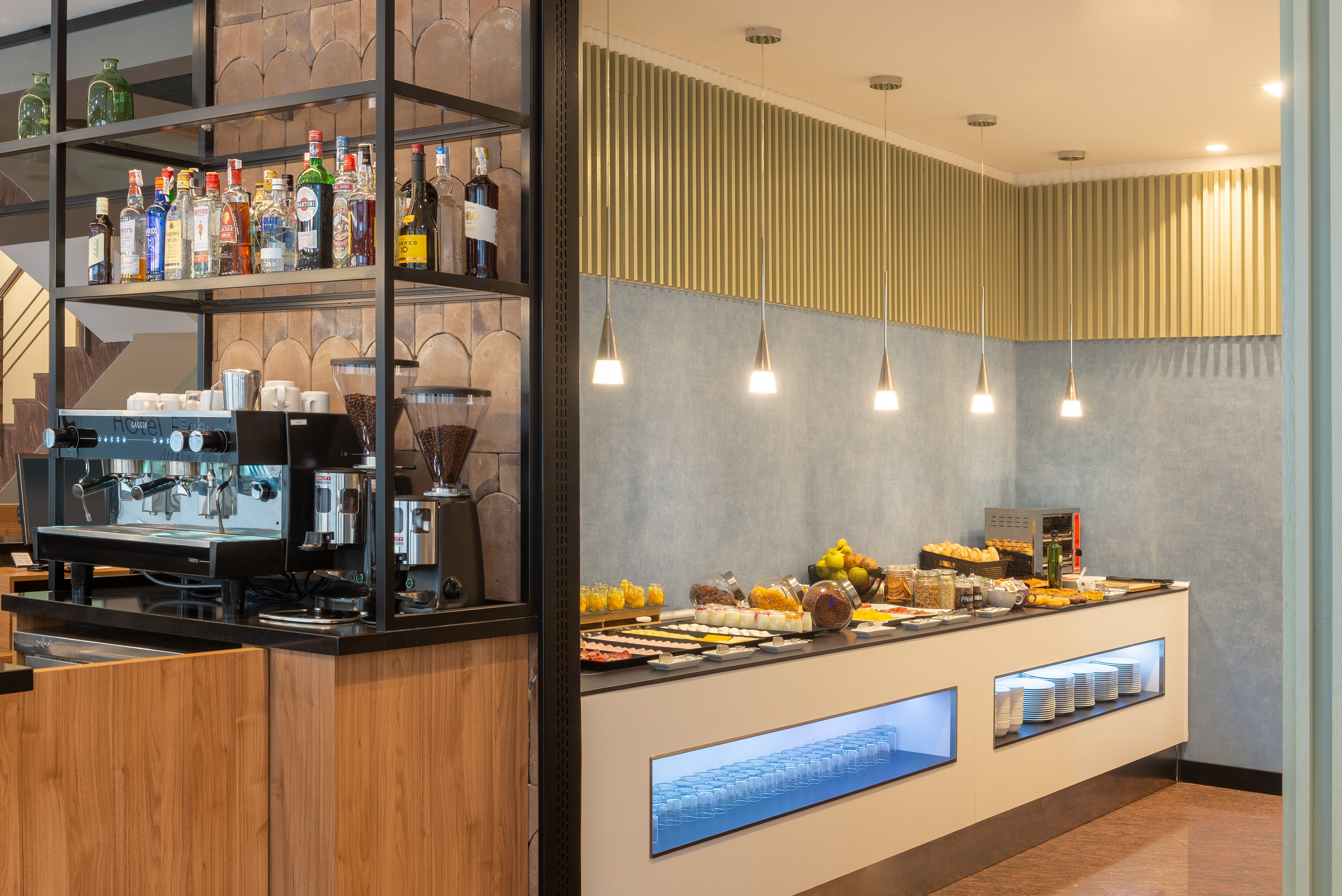 Modern hotel breakfast buffet with fresh food, coffee machine, and bar.