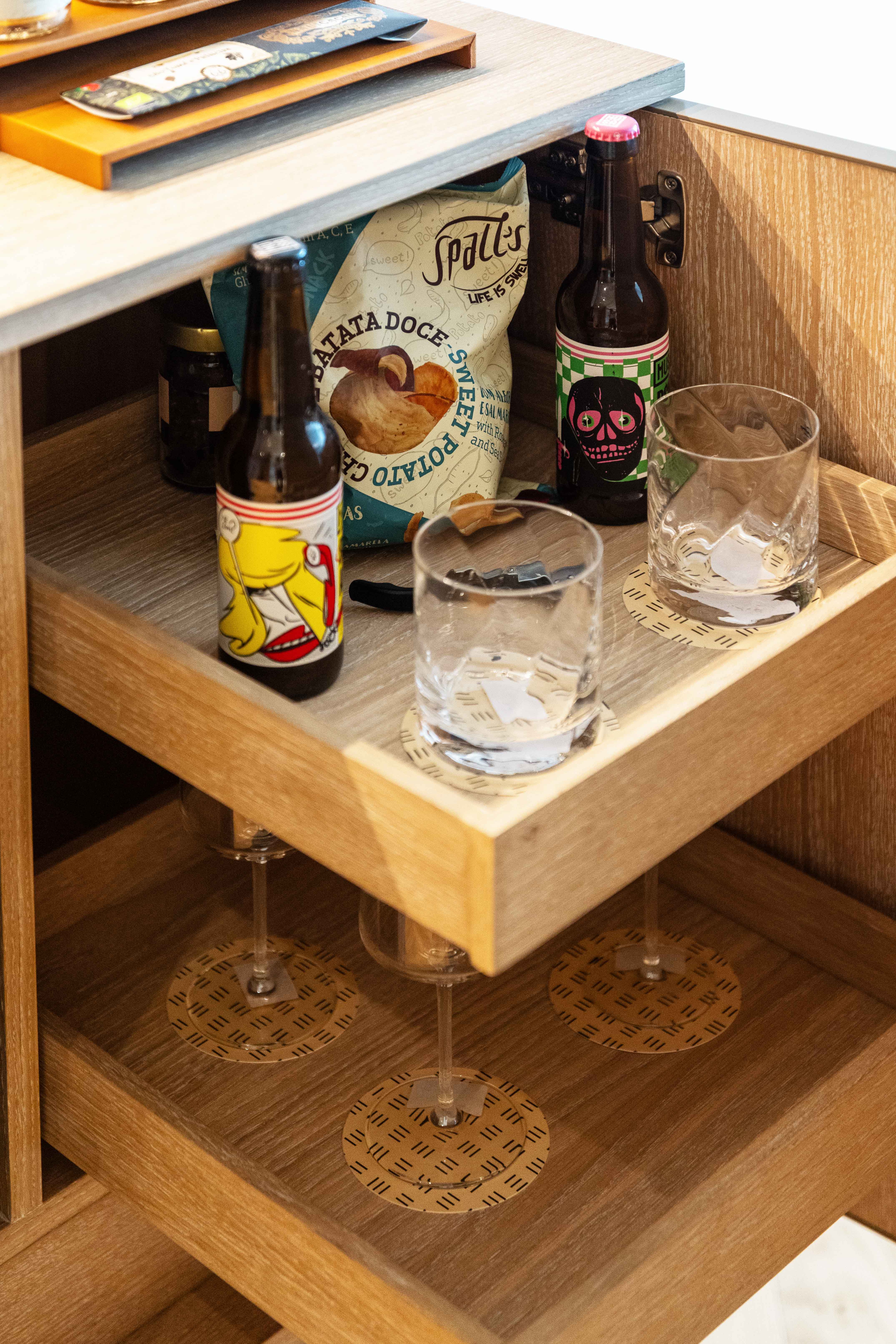 Modern wooden mini-bar with craft beer, sweet potato chips, and crystal glasses.
