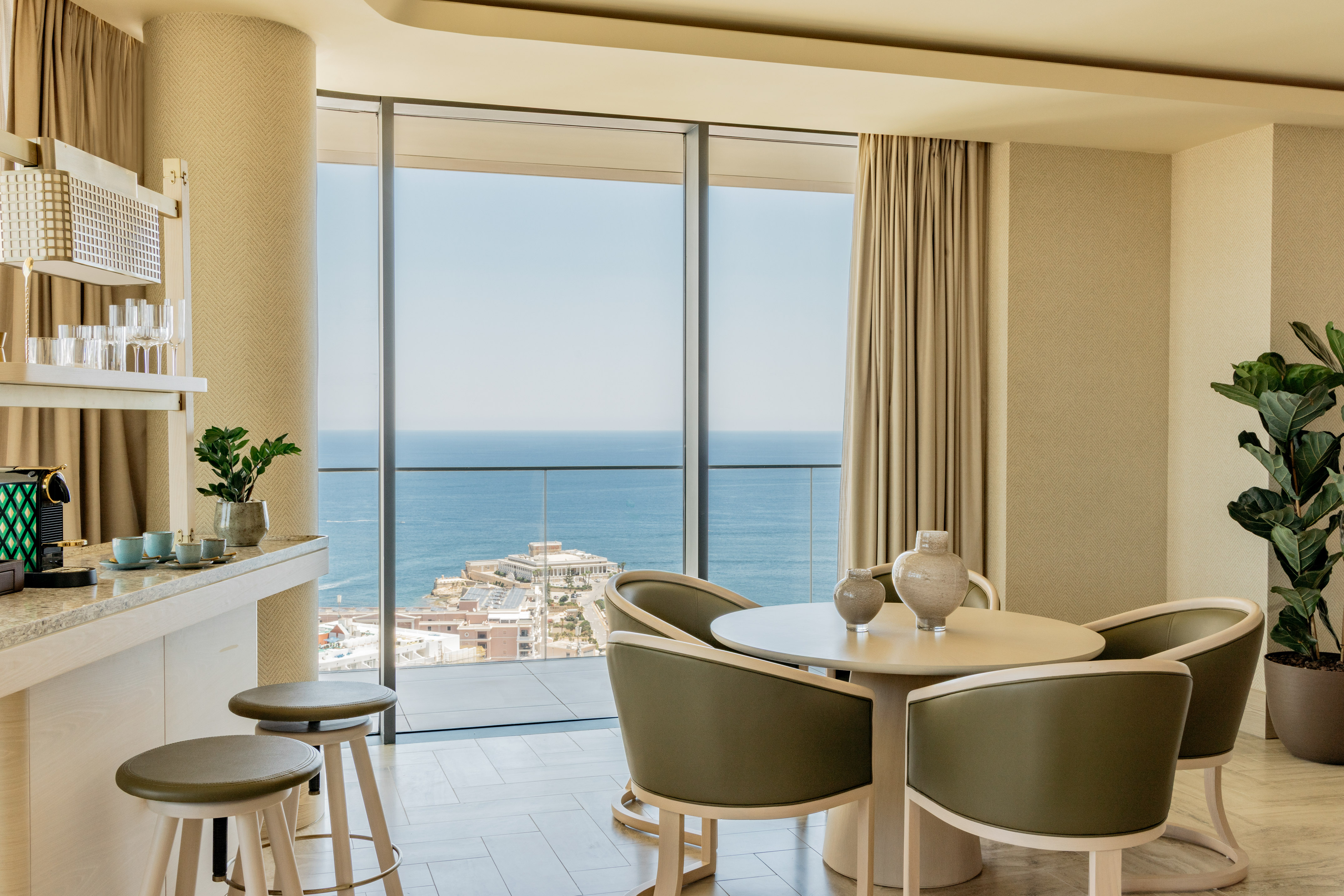 Luxury hotel suite with ocean view, modern dining and bar.