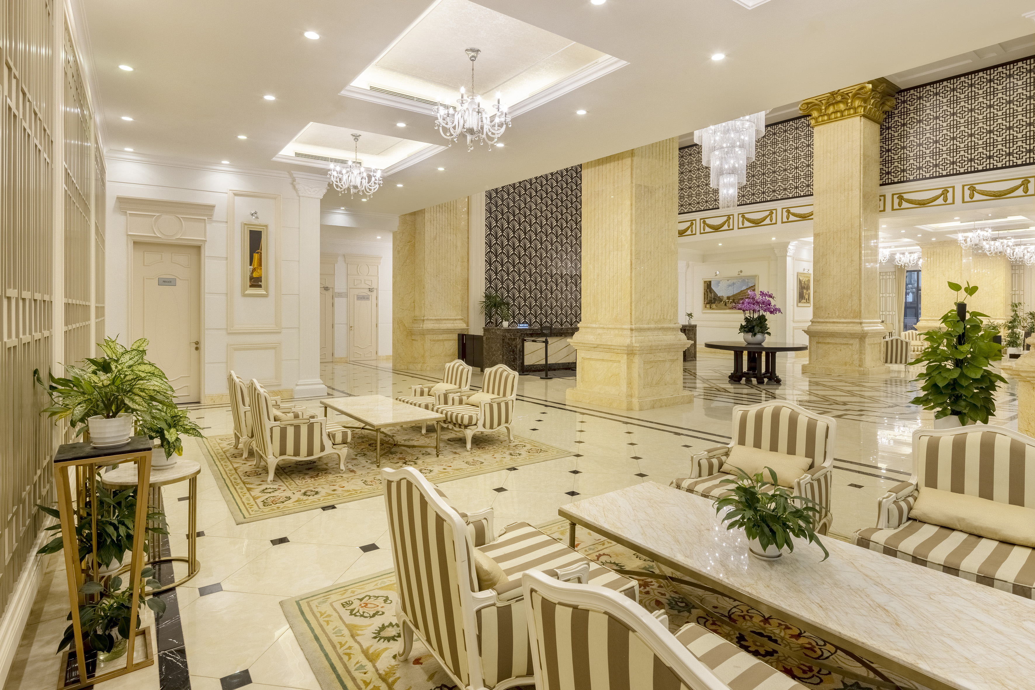 Luxury hotel lobby with elegant seating, marble columns, and chandeliers.