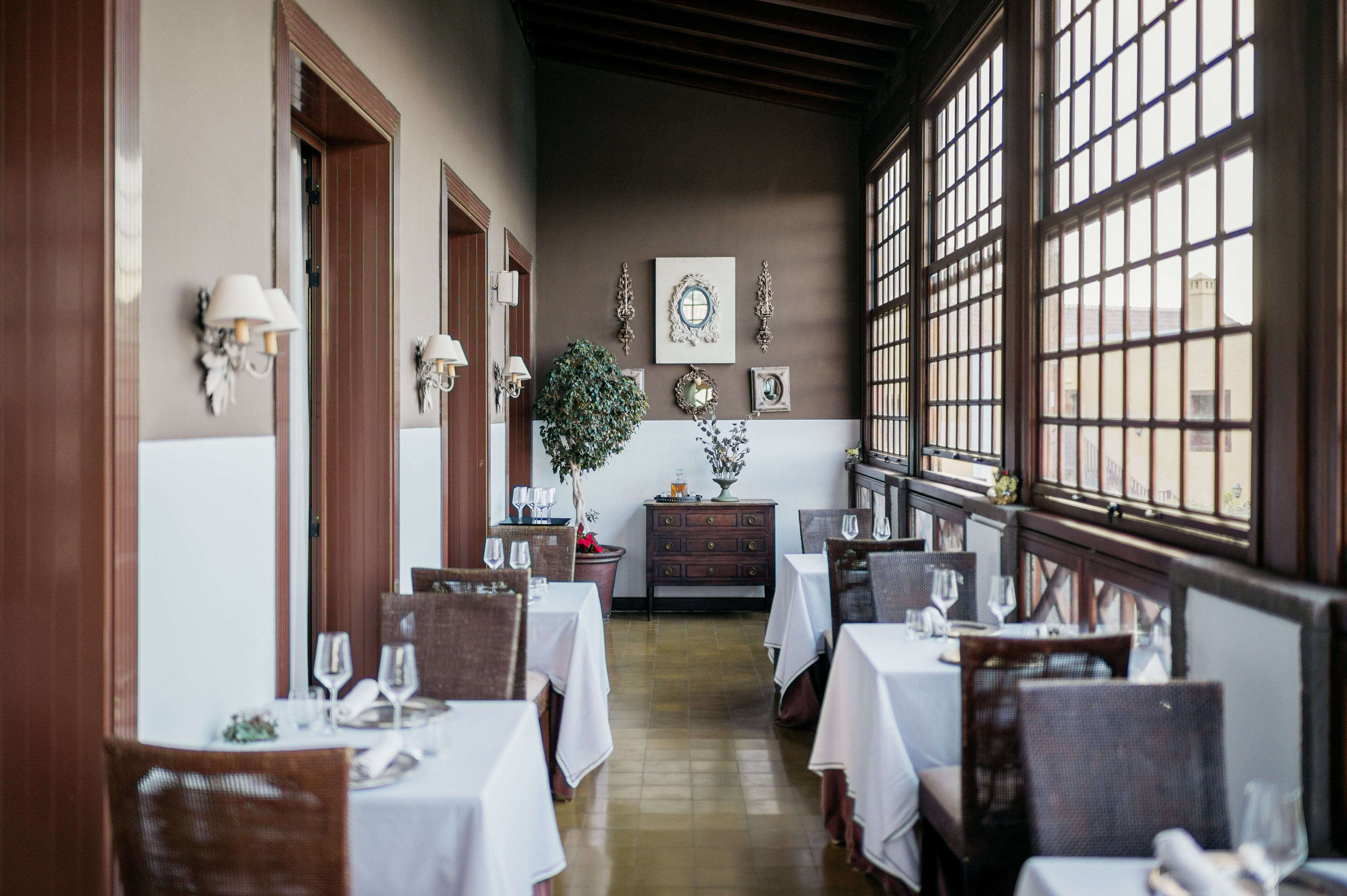 Elegant restaurant dining room with set tables and large wooden windows.