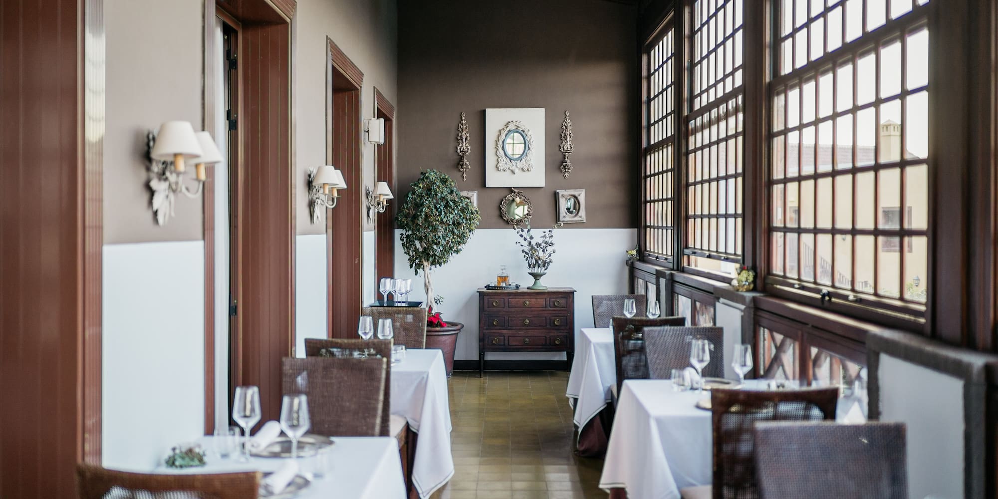 Elegant restaurant dining room with set tables and large wooden windows.