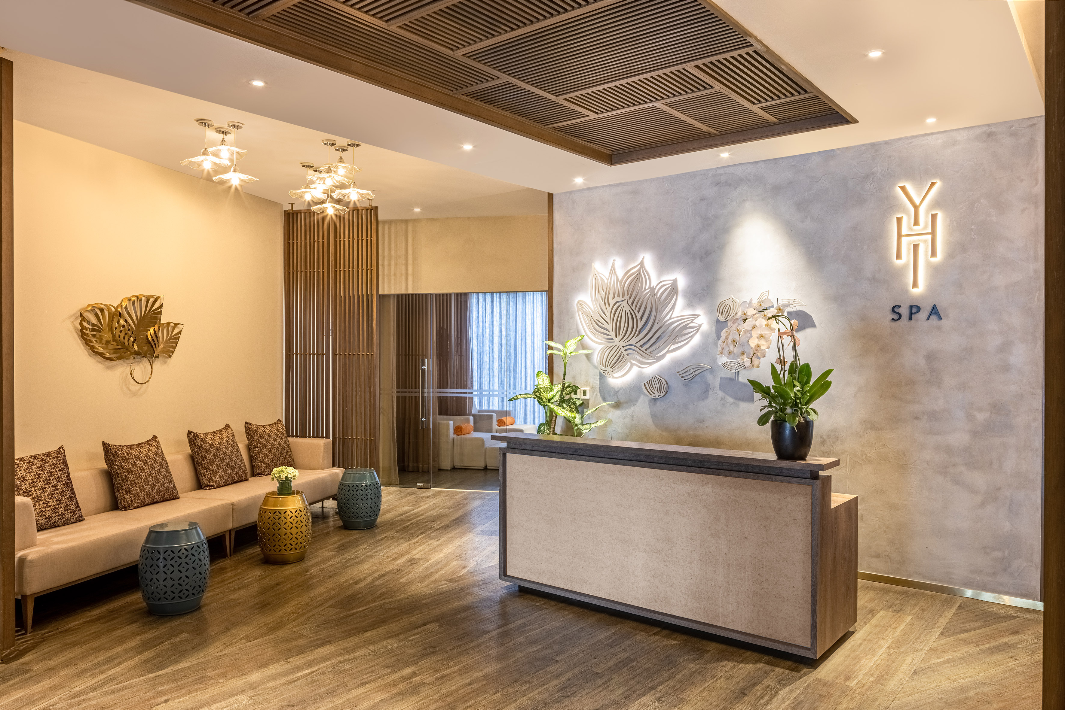 Modern spa reception with lotus wall art, comfortable seating, and wooden decor.