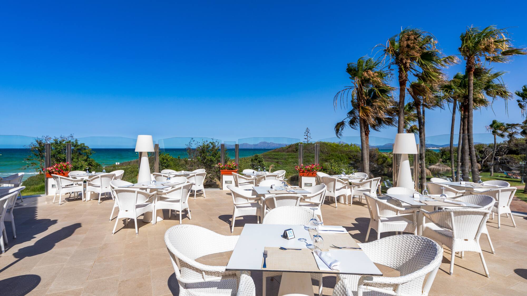 a white tables and chairs on a patio with a body of water in the background
