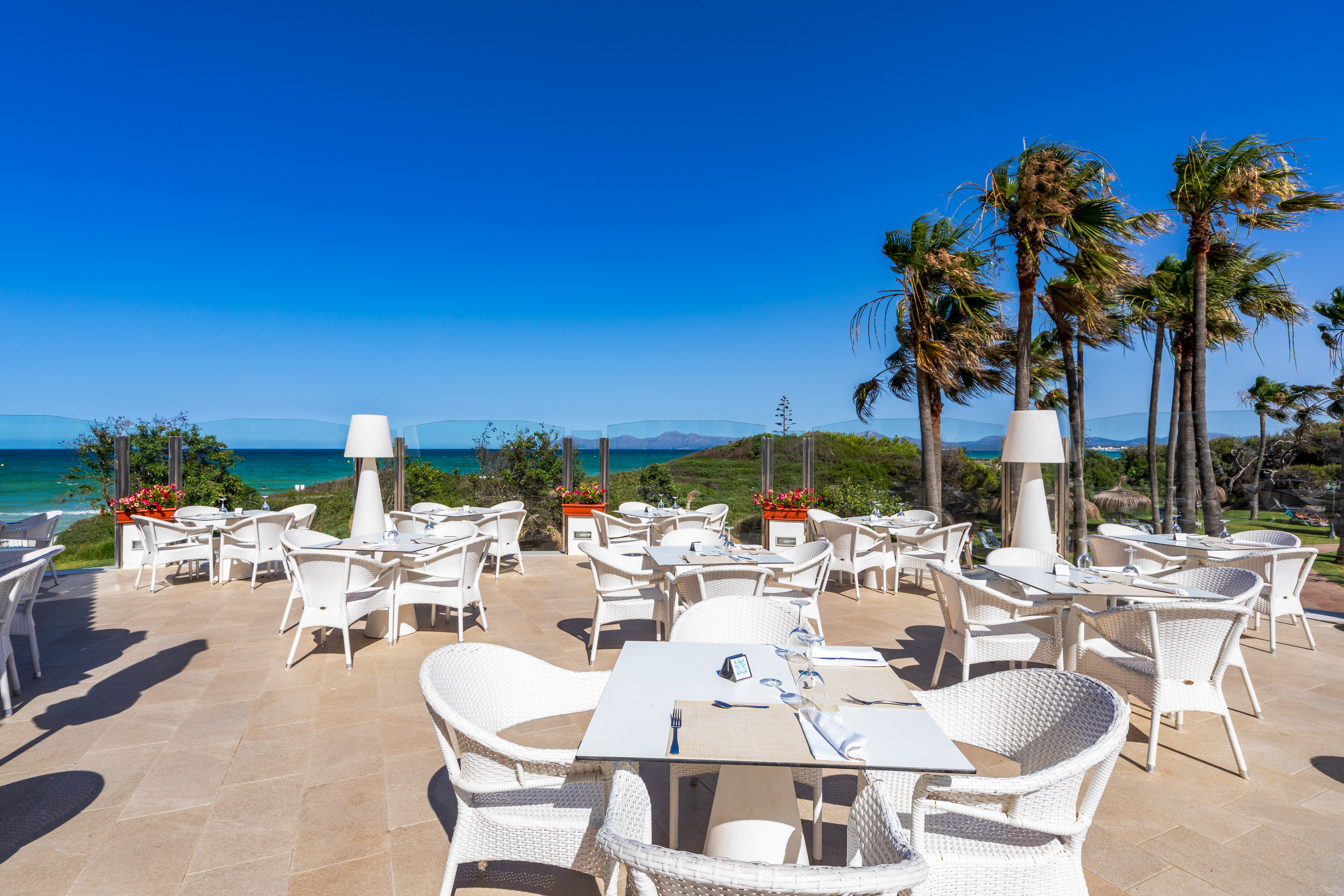 a white tables and chairs on a patio with a body of water in the background