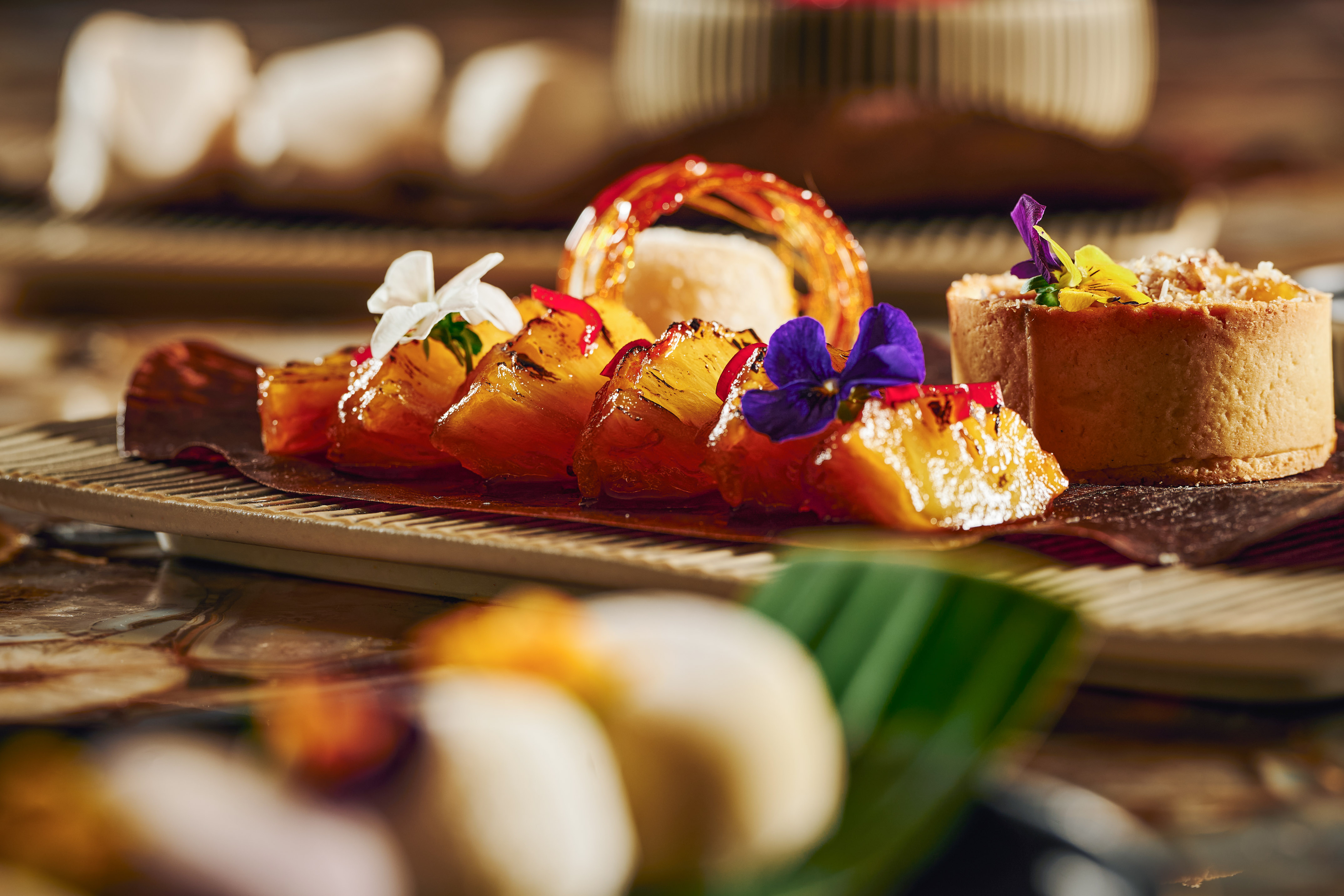 Gourmet glazed pineapple slices with edible flowers, tropical fruit tart dessert.
