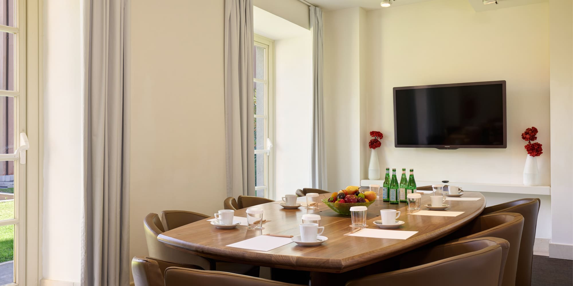 a table with a bowl of fruit and a television on the wall