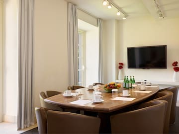 a table with a bowl of fruit and a television on the wall