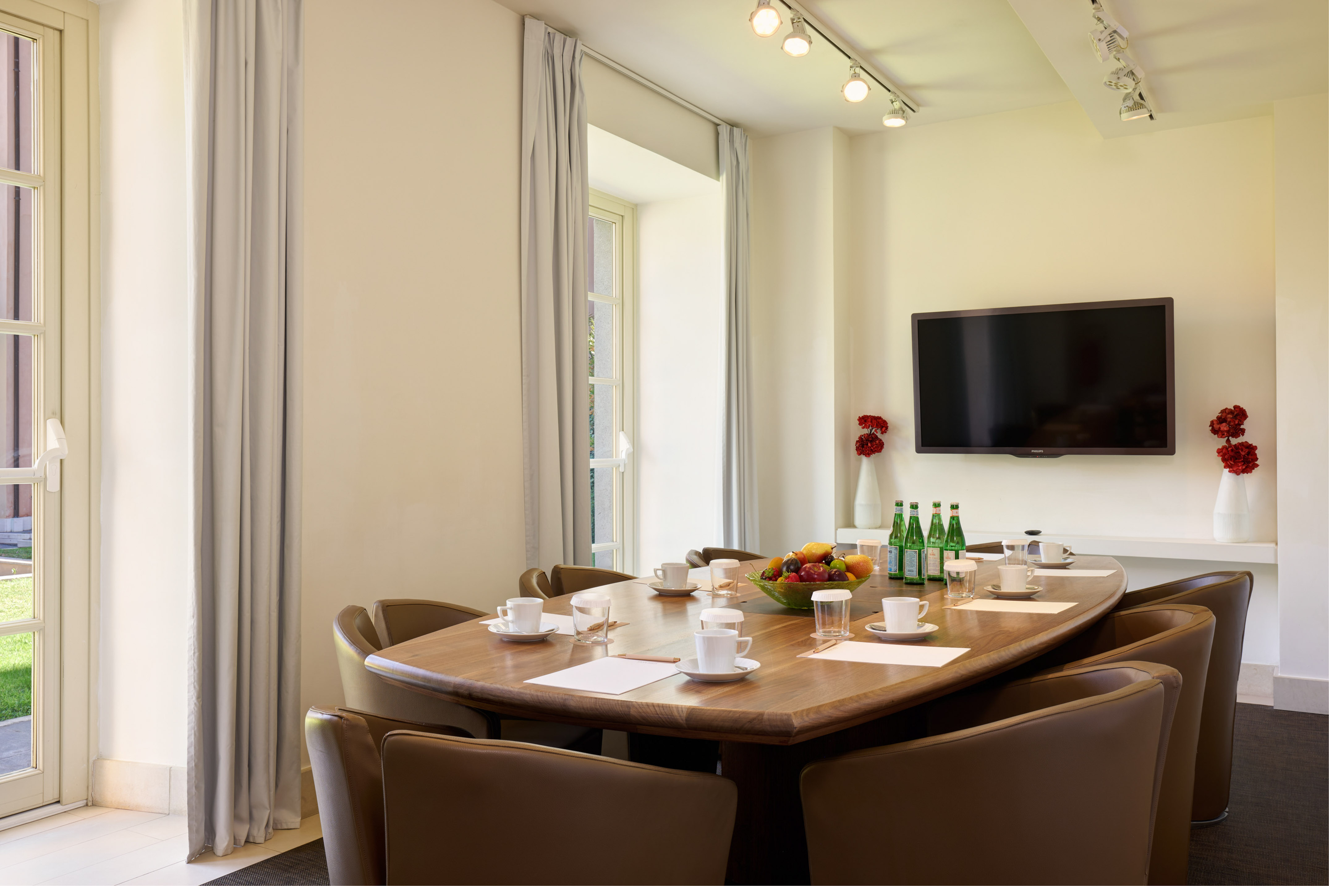 Elegant conference room with wooden table, brown chairs, wall-mounted TV.