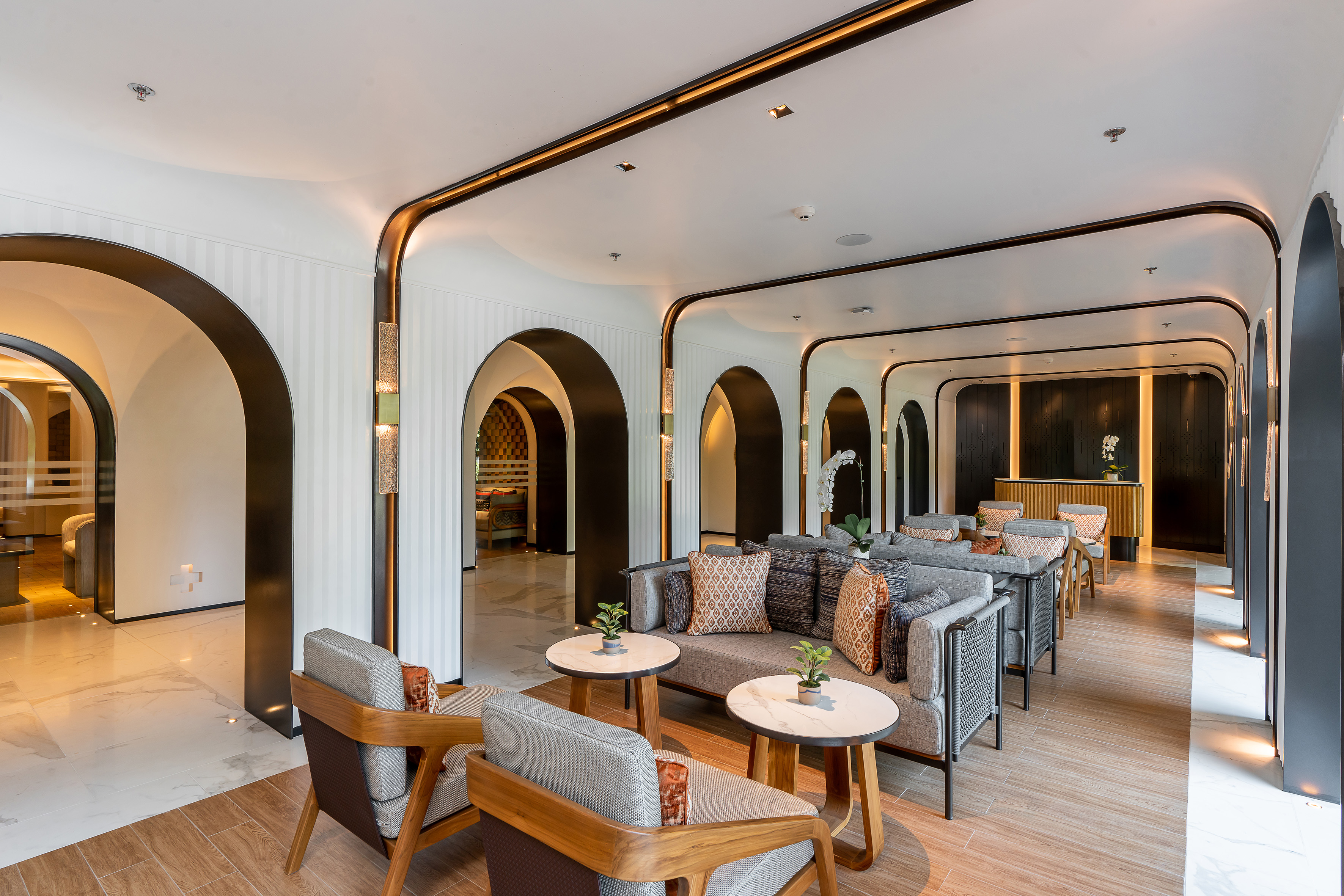 Modern hotel lounge with elegant seating, arched corridors, and contemporary lighting.