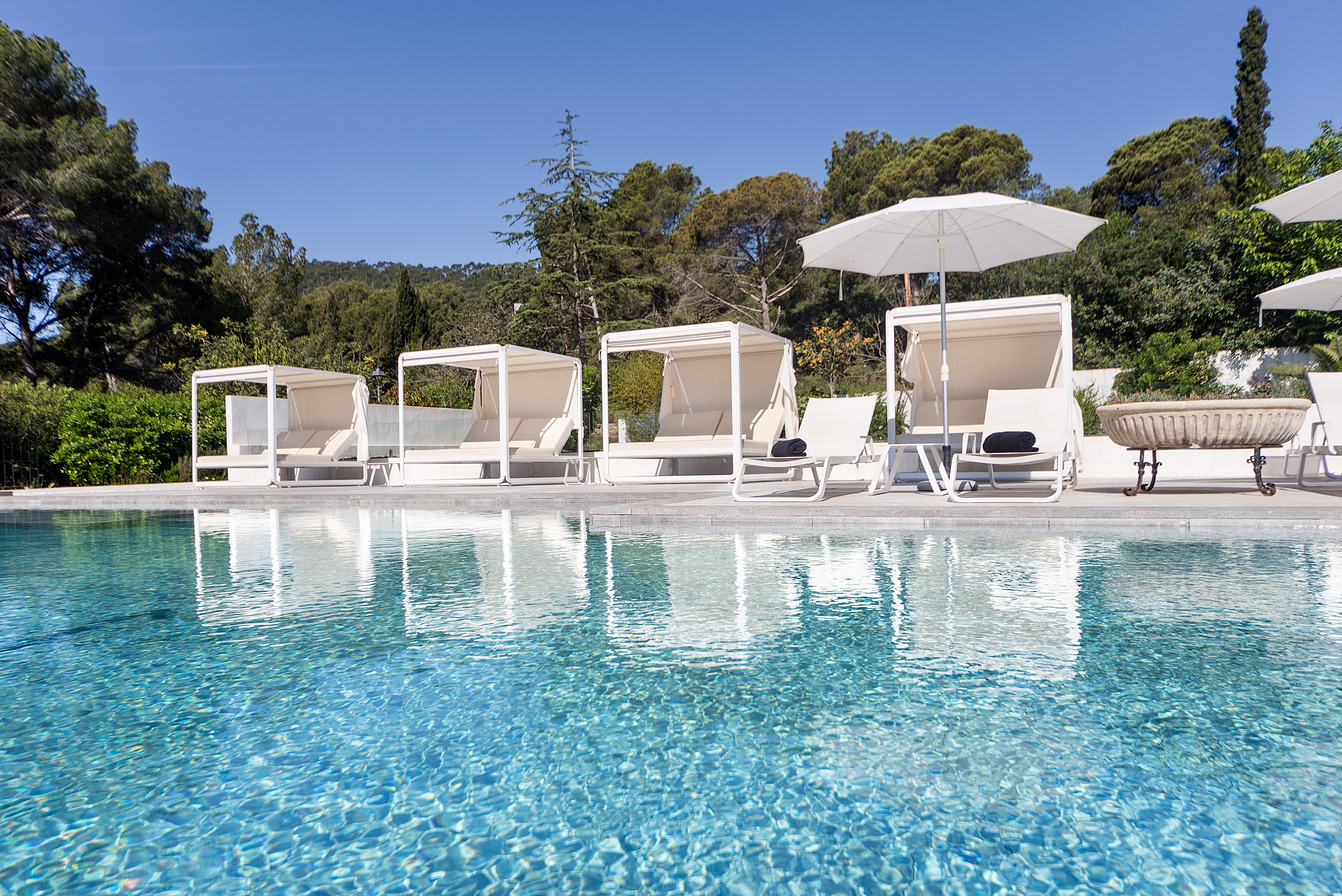 Luxury pool with white cabanas, sun loungers, and clear blue water.