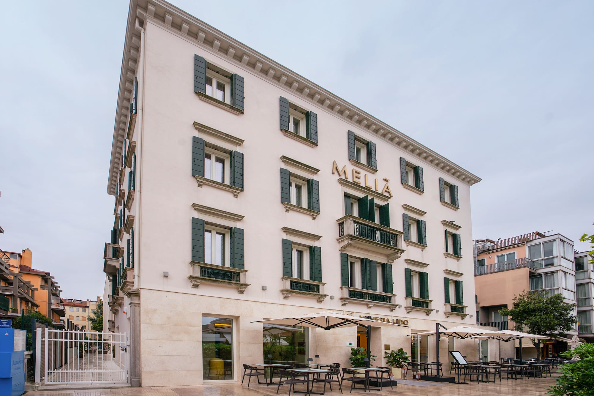Melia Venezia Lido hotel exterior with green shutters and outdoor cafe seating.