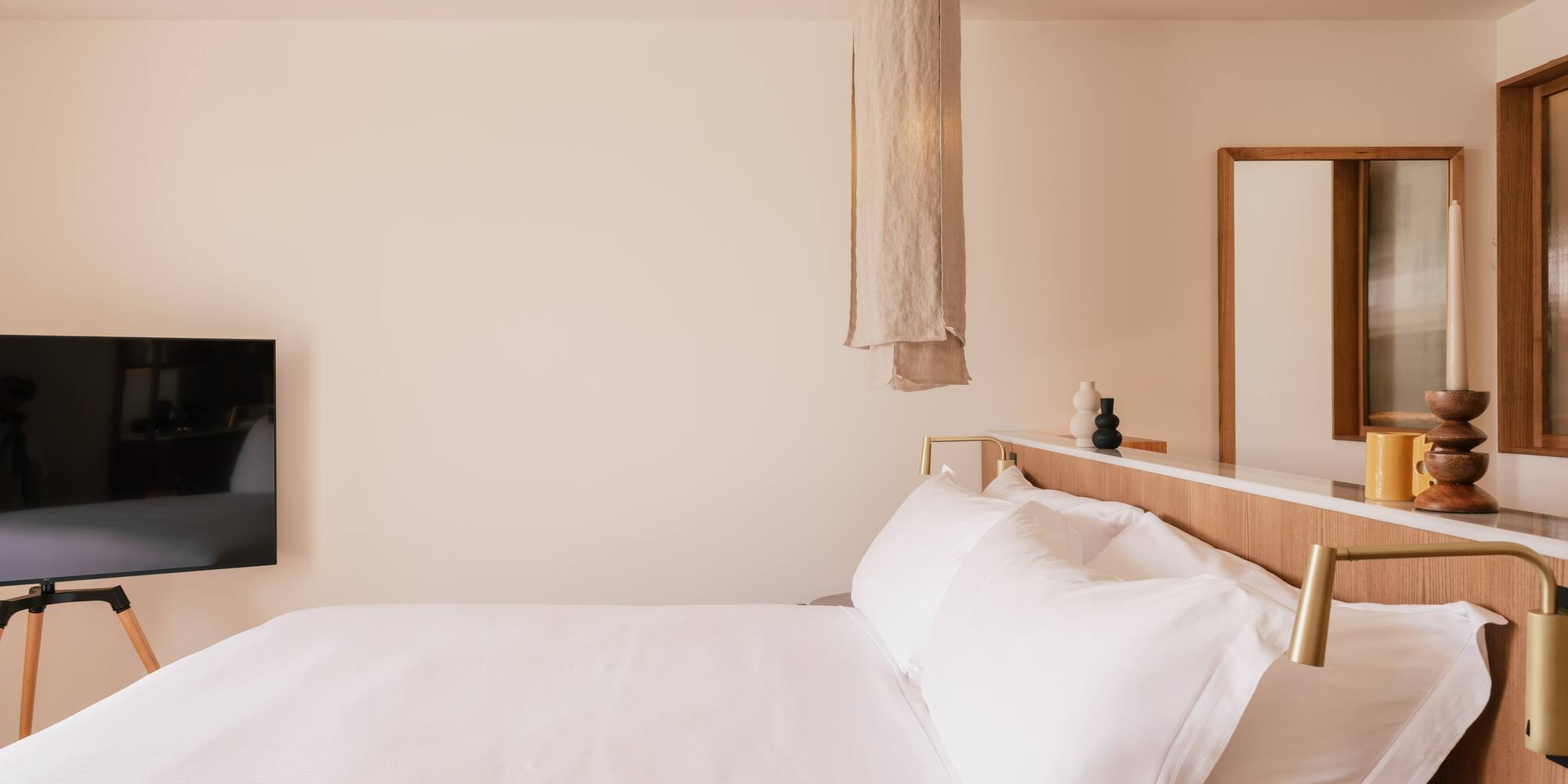 a bed with white sheets and a mirror