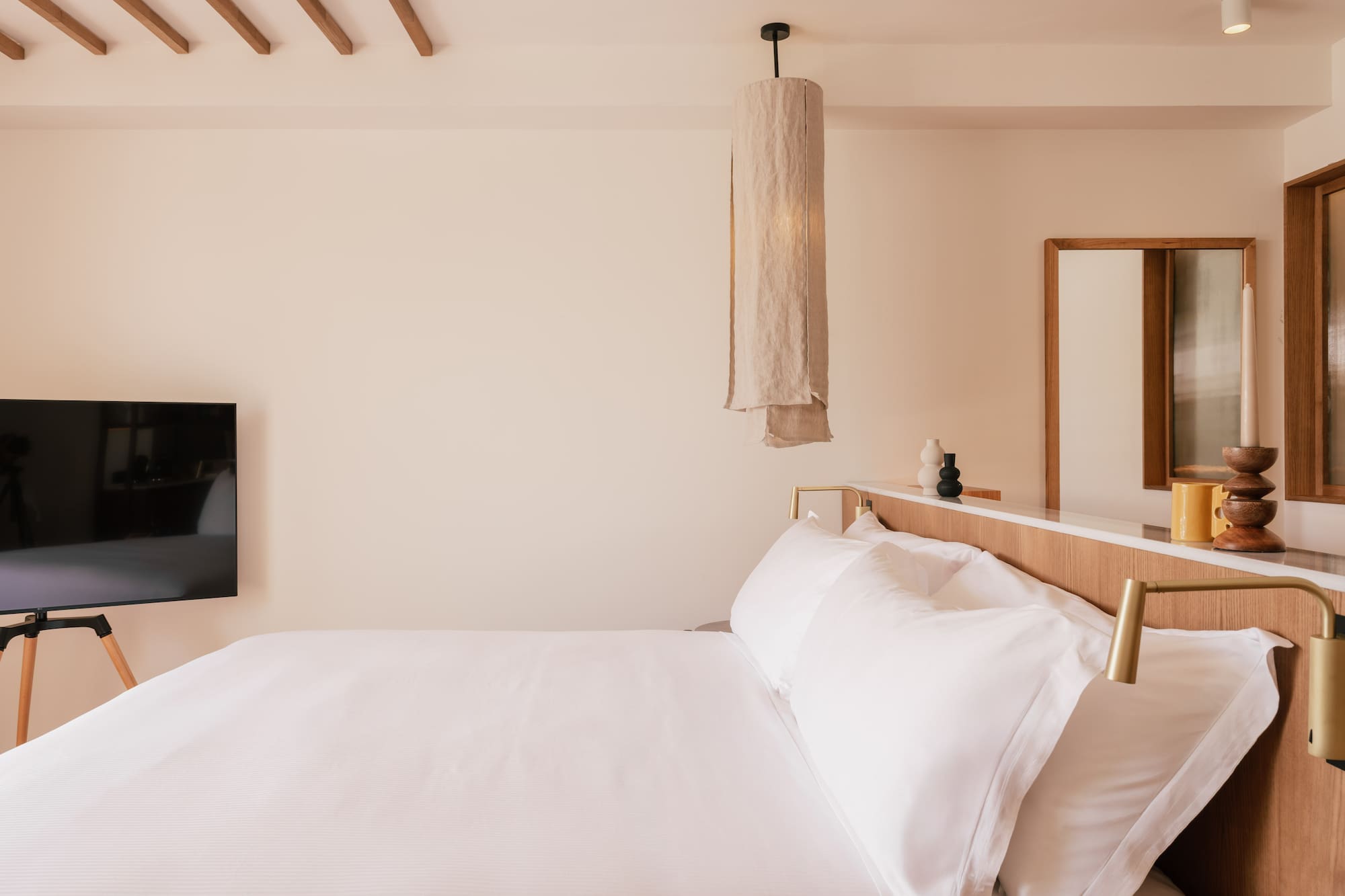 a bed with white sheets and a mirror