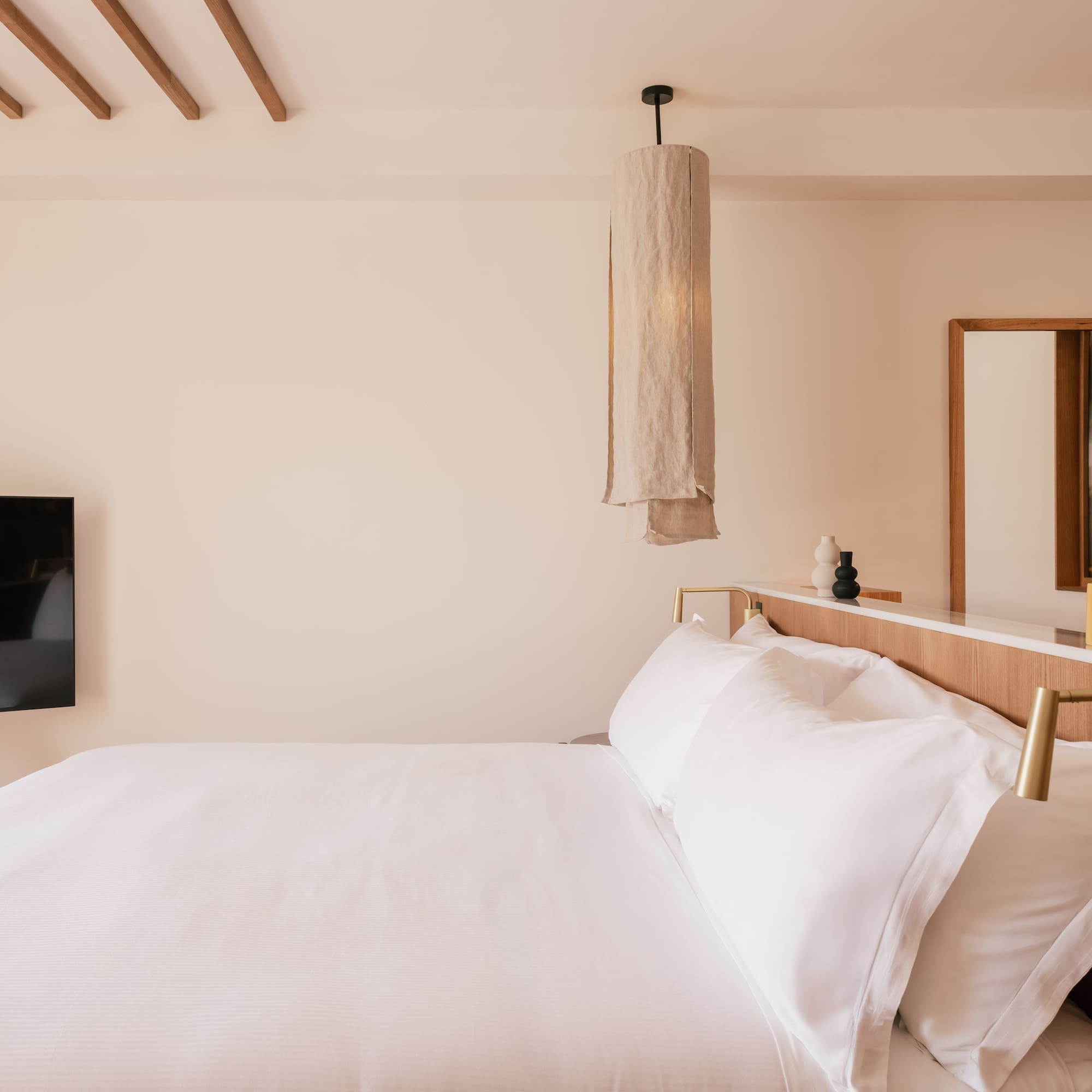 a bed with white sheets and a mirror