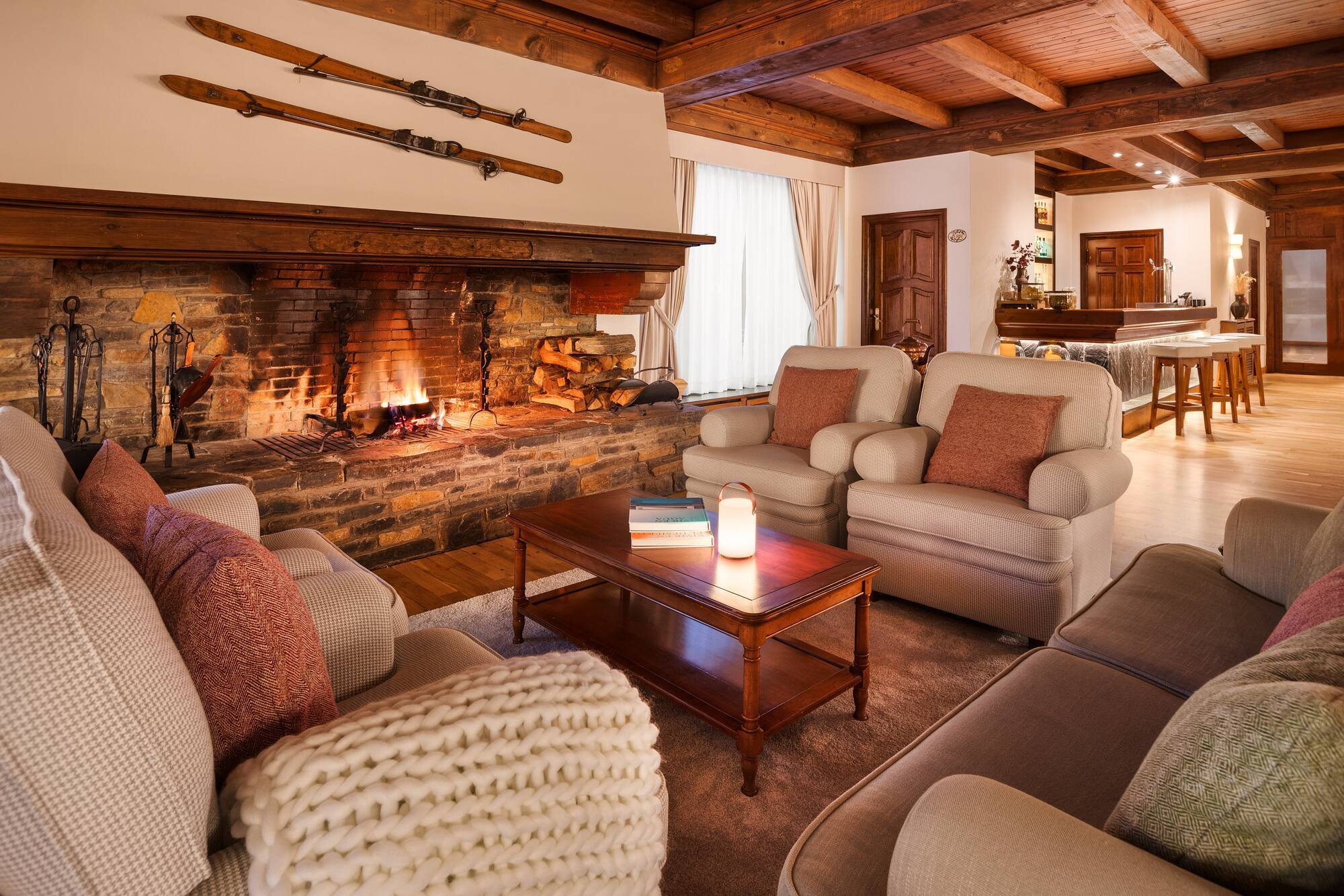 Warm ski lodge lounge with stone fireplace, vintage skis, and comfortable seating.
