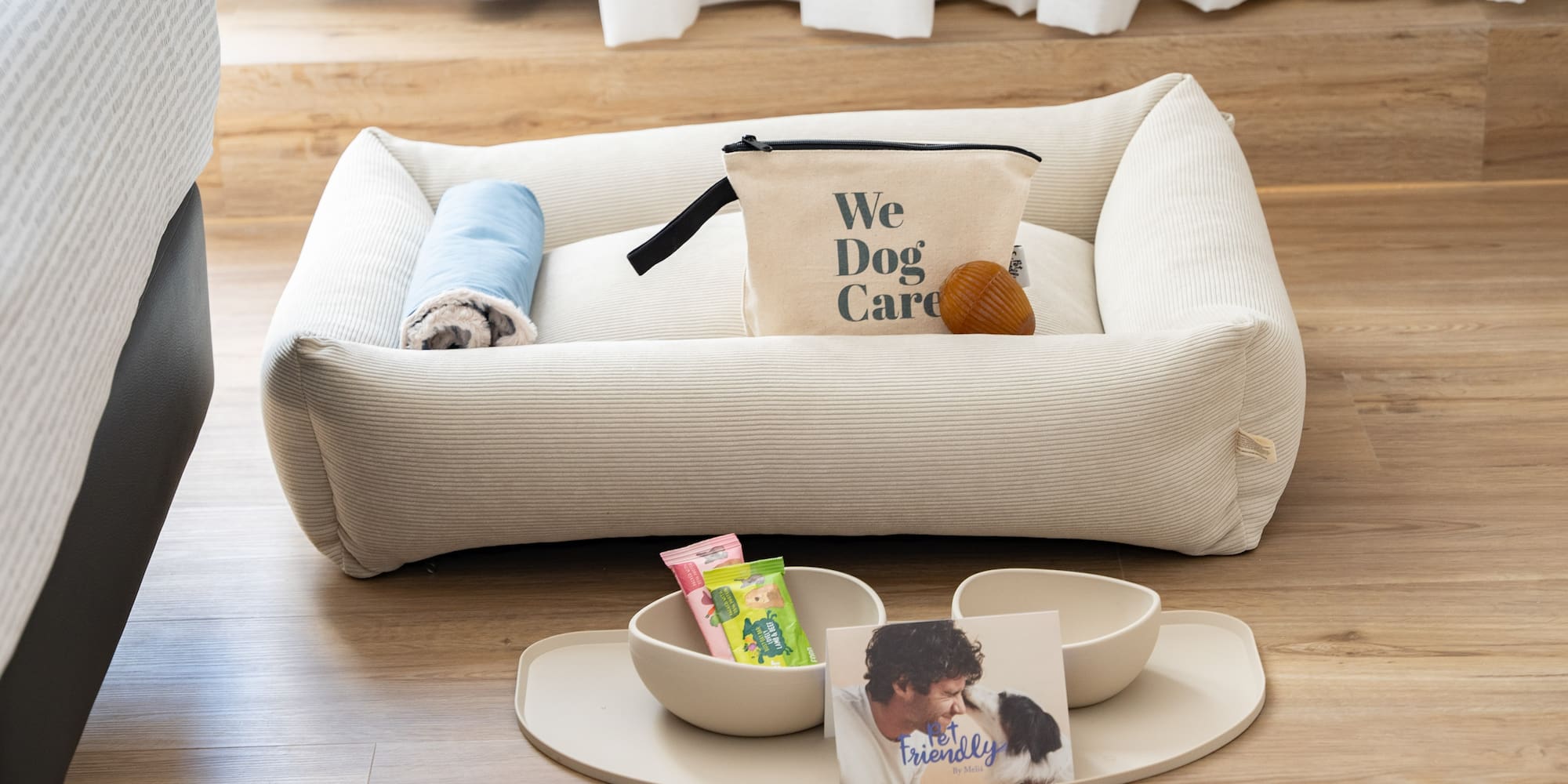 Pet-friendly hotel: dog bed, blanket, 'We Dog Care' kit, bowls, and treats.