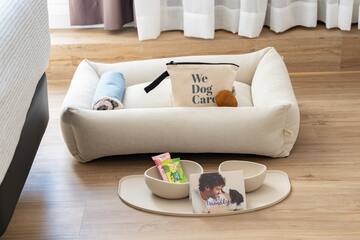 a dog bed with a bag and bowls on a tray