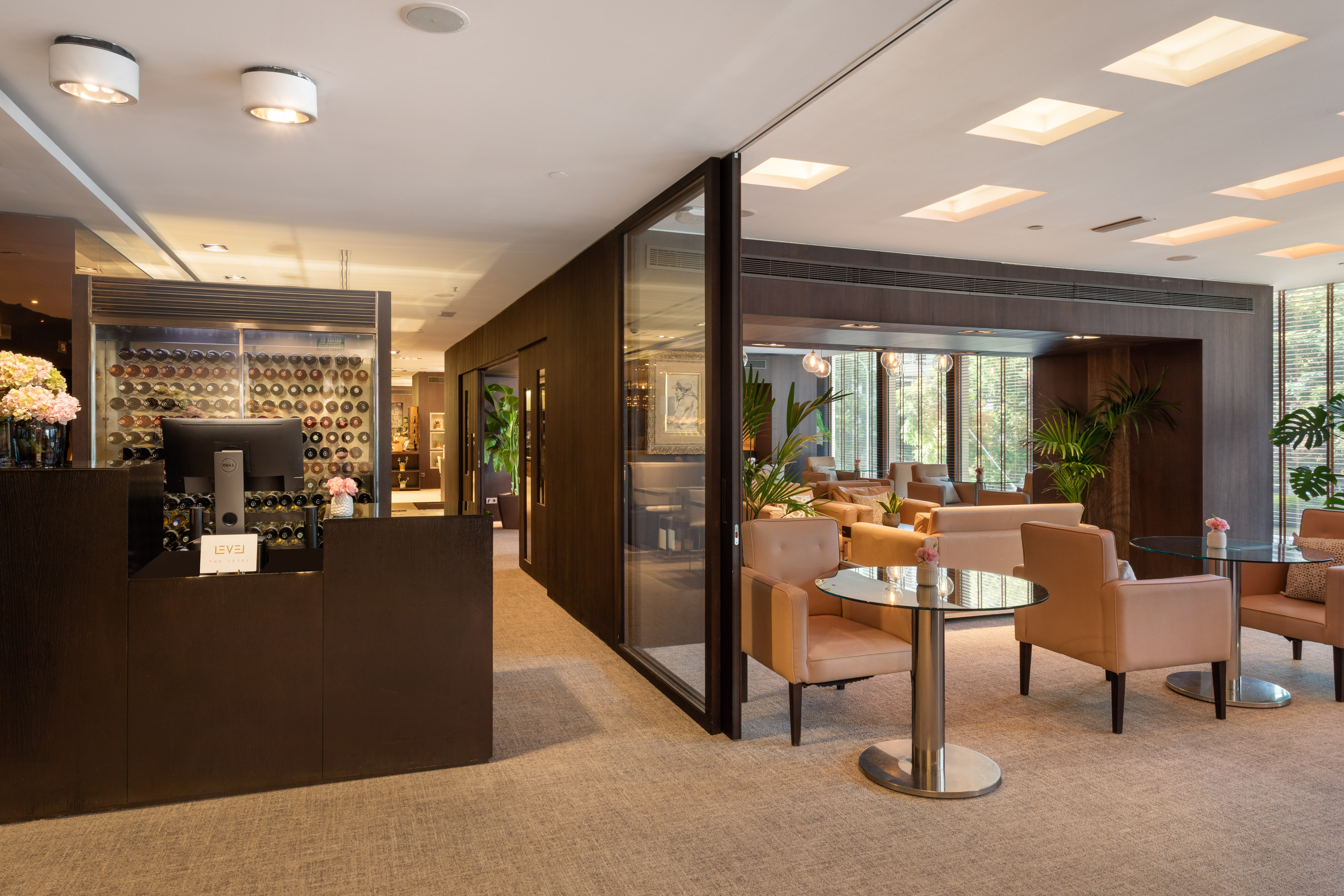 Hotel lounge bar with wine display, reception desk, and tan seating.