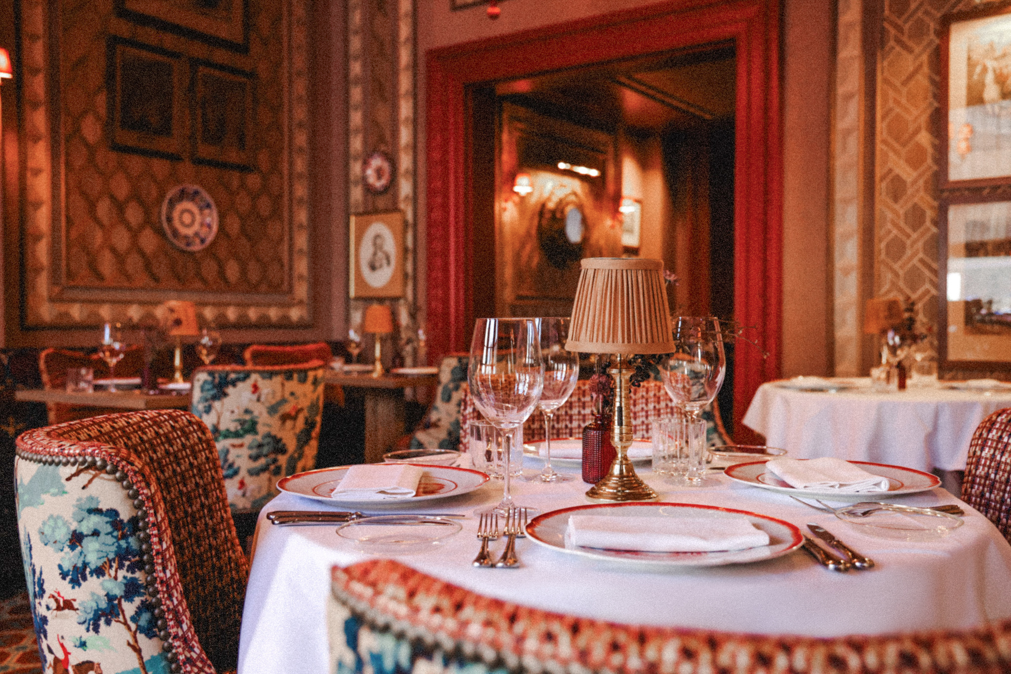 Mesa de comedor elegante con vajilla, copas y lámpara. Interior de restaurante lujoso.