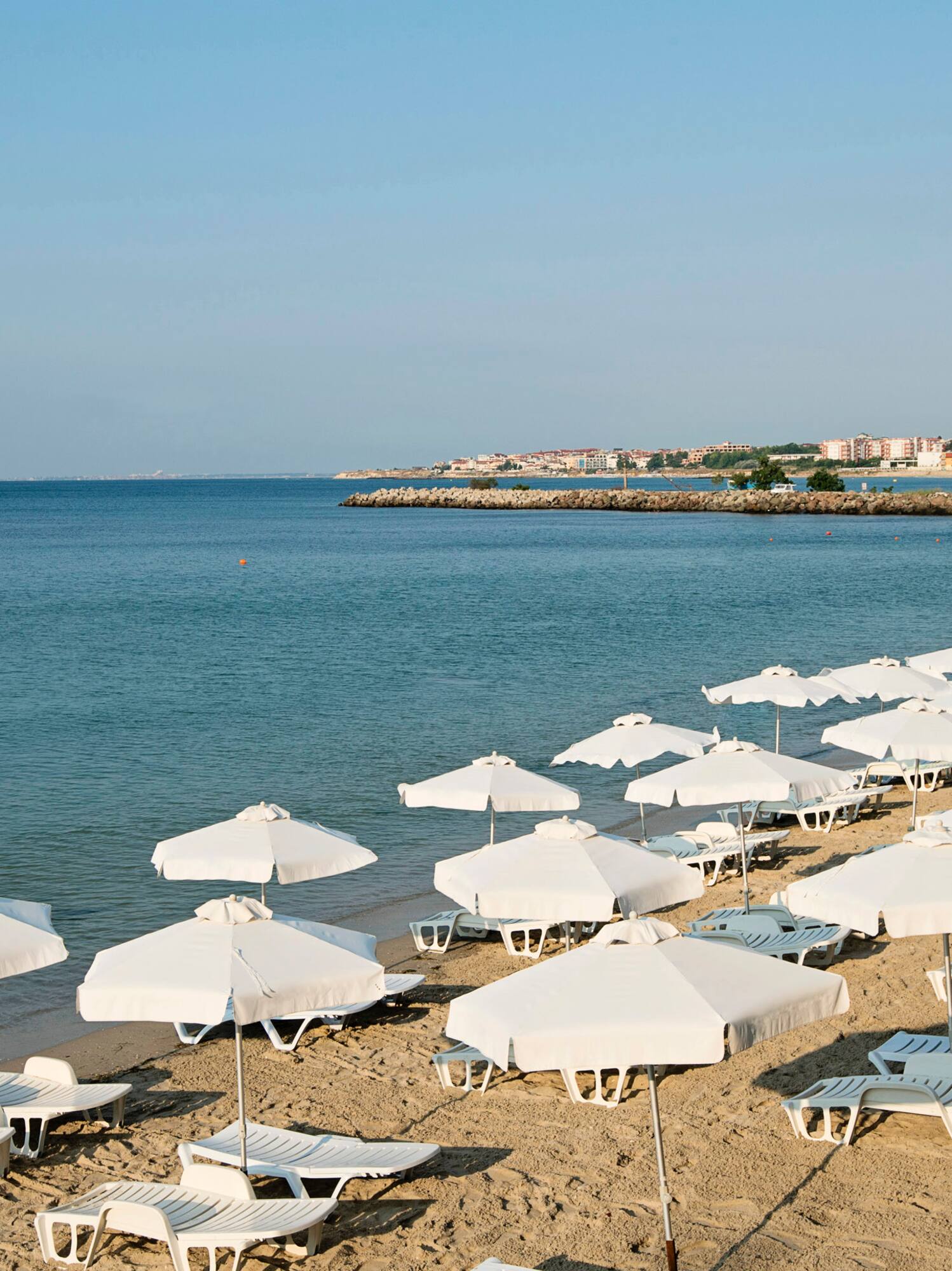 a beach with white umbrellas and lounge chairs
