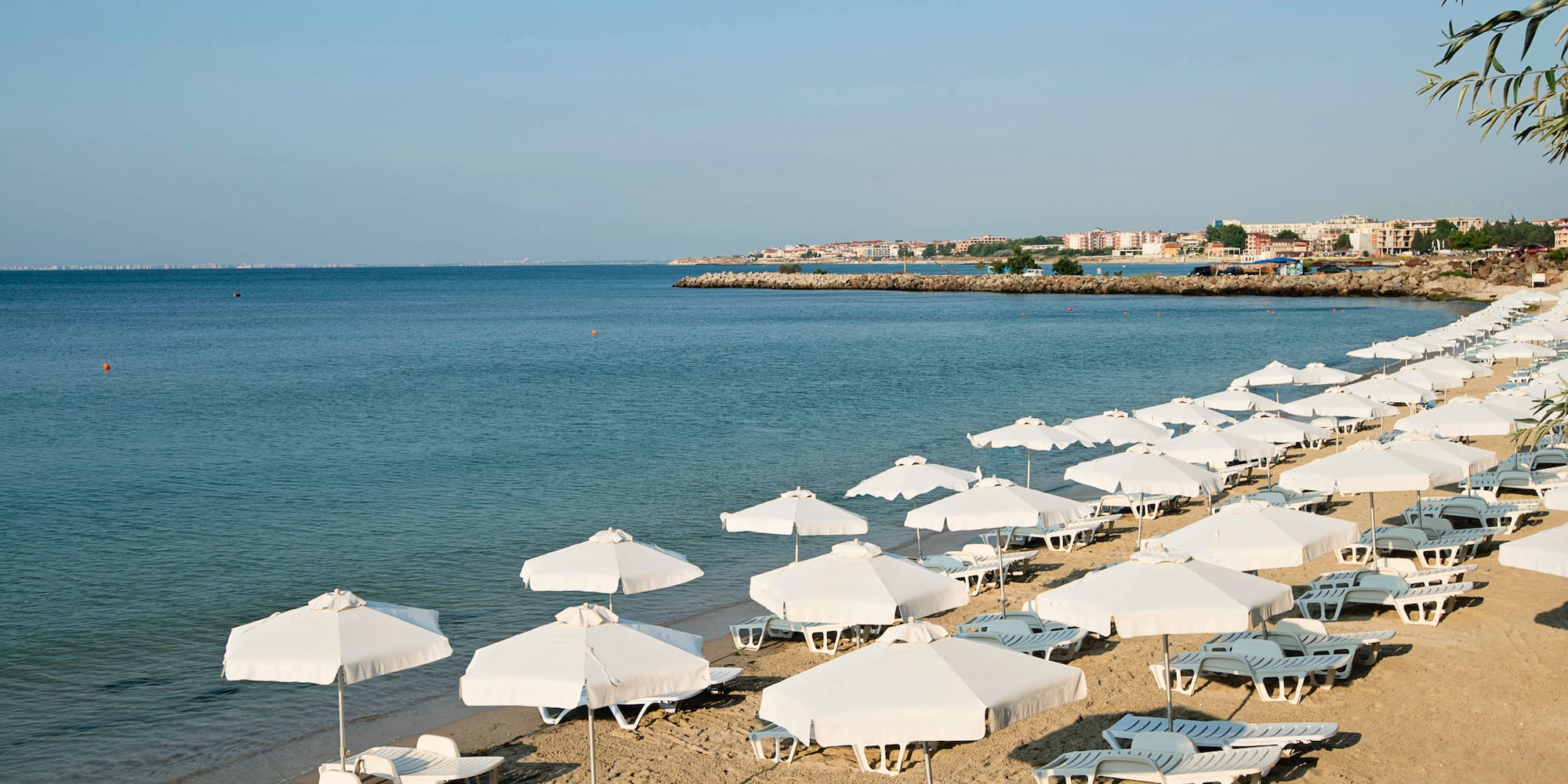 a beach with white umbrellas and lounge chairs