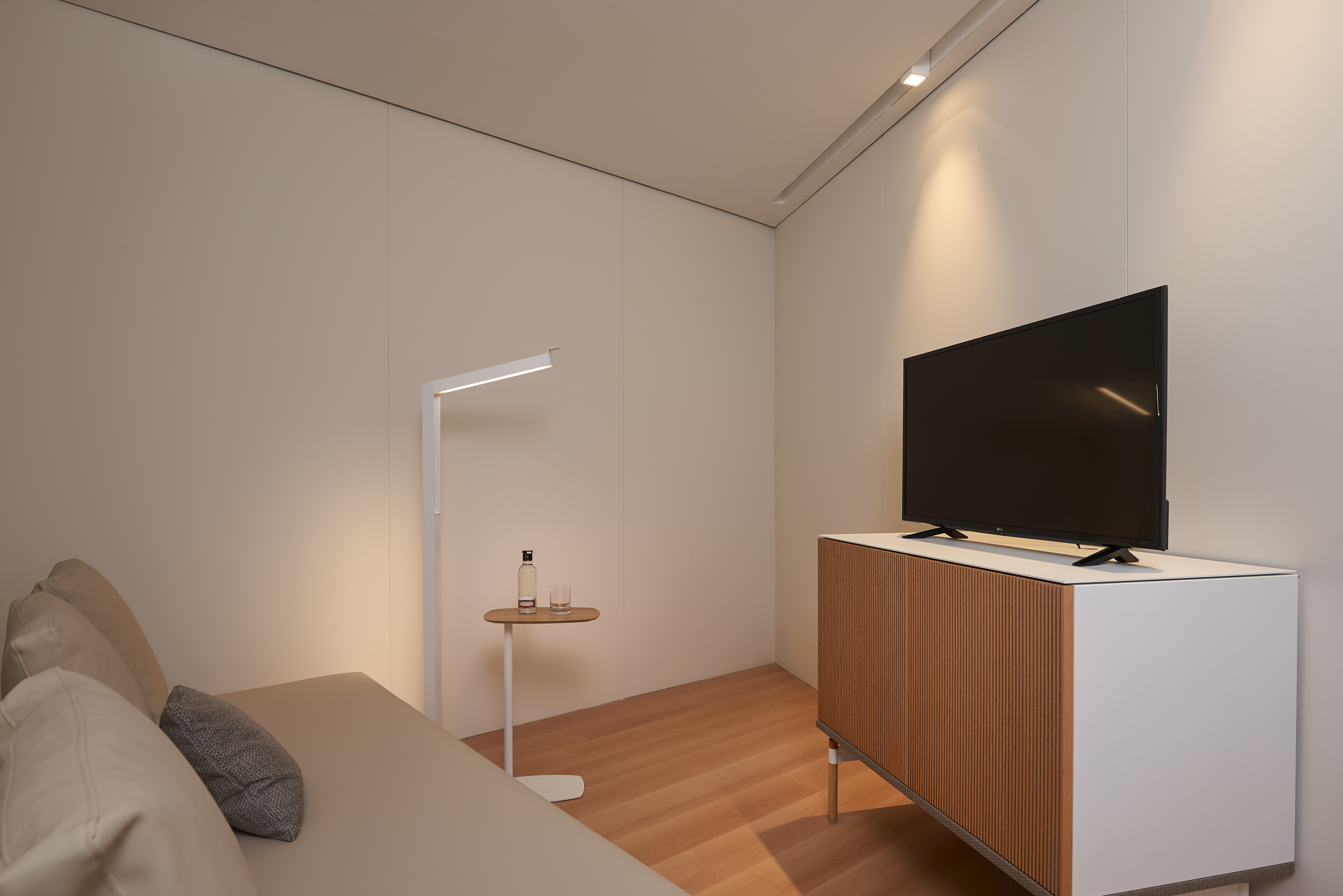 Modern minimalist room with sofa, sleek floor lamp, and wood TV console.