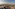 Rooftop bar with city and mountain view at sunset.