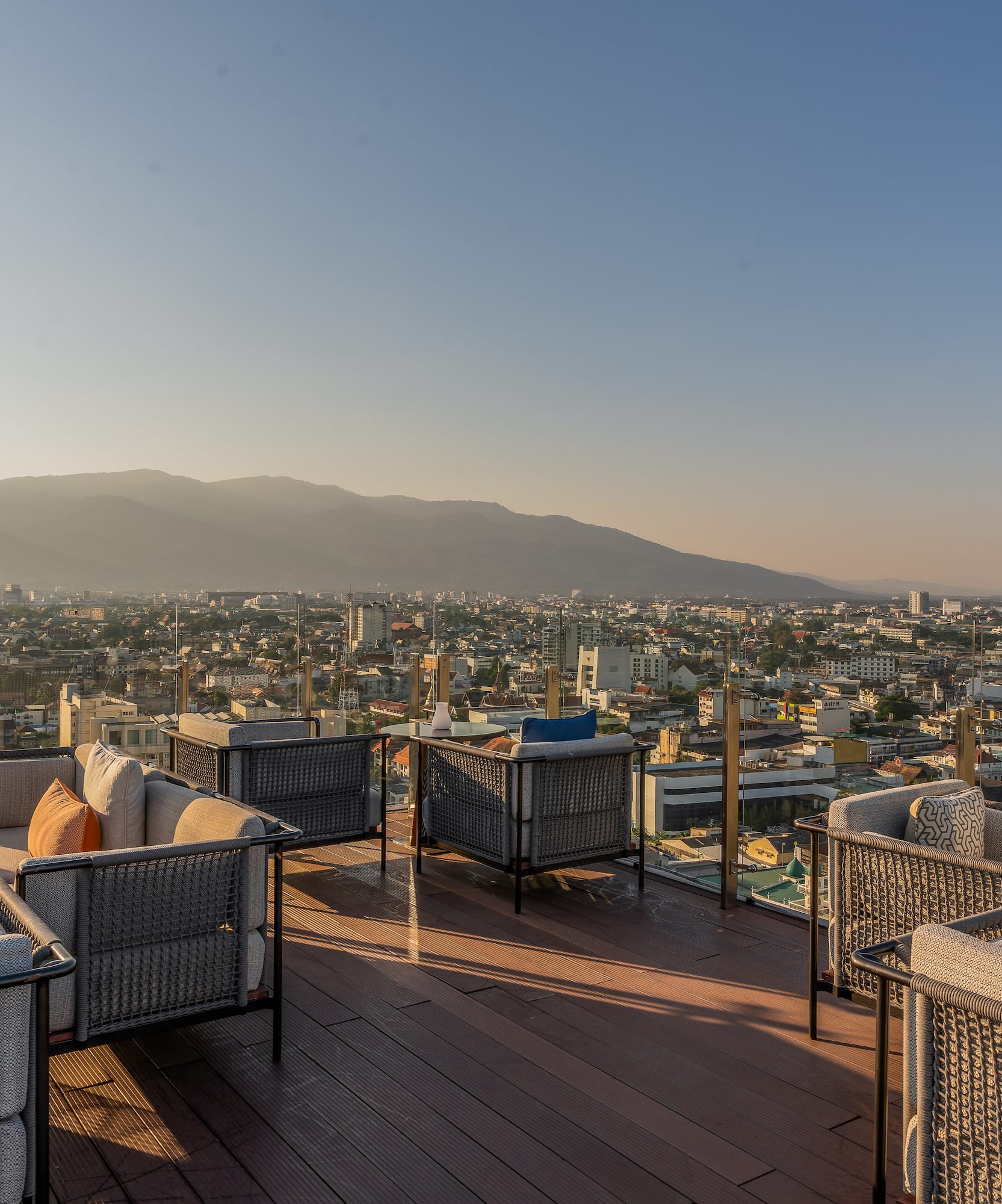 Rooftop bar with city and mountain view at sunset.