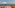 Terracotta rooftop terrace with ocean view, two sun loungers, and white sun umbrella.