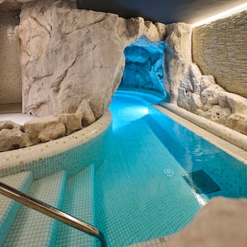 a swimming pool with a rock wall and a cave