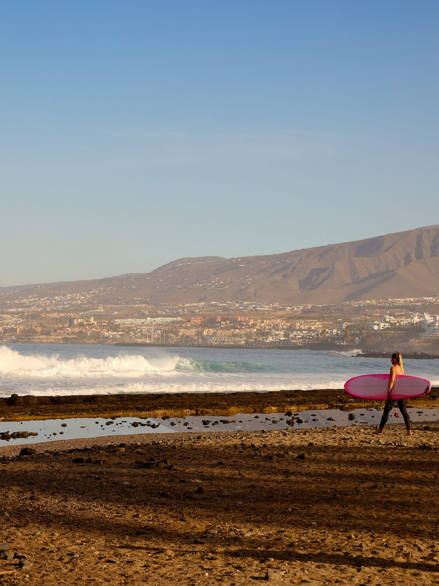 a woman carrying a surfboard on a beach