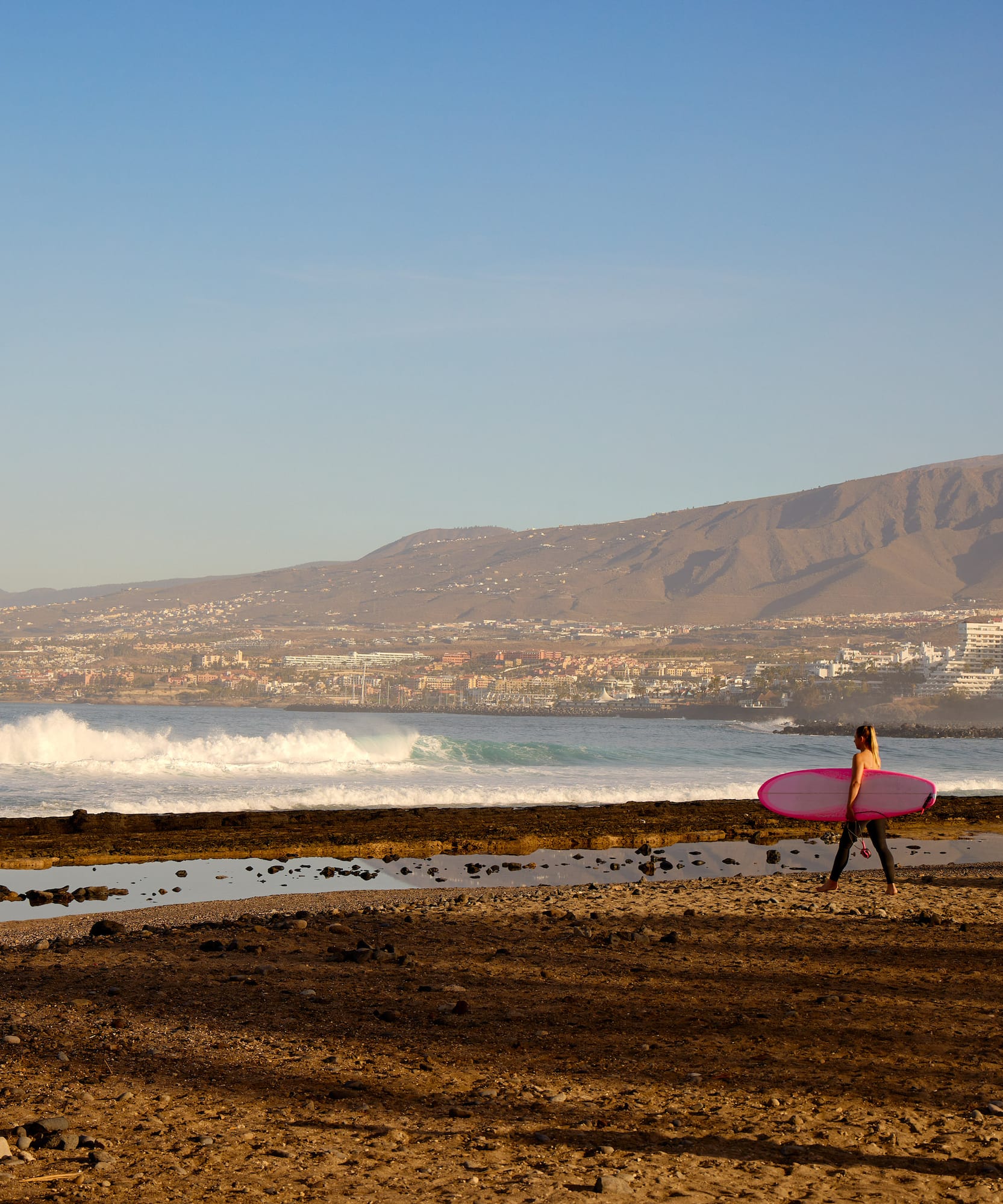 a woman carrying a surfboard on a beach