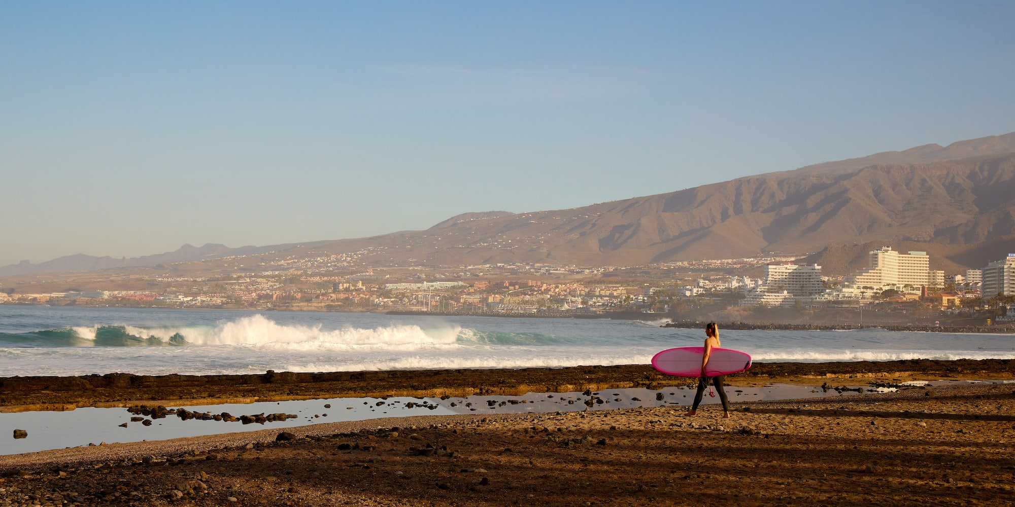 a woman carrying a surfboard on a beach