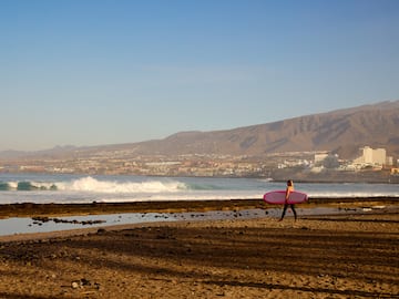 a woman carrying a surfboard on a beach