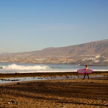 a woman carrying a surfboard on a beach