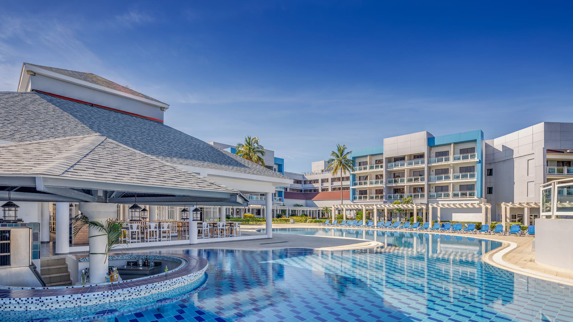 a pool with chairs and a bar in the background