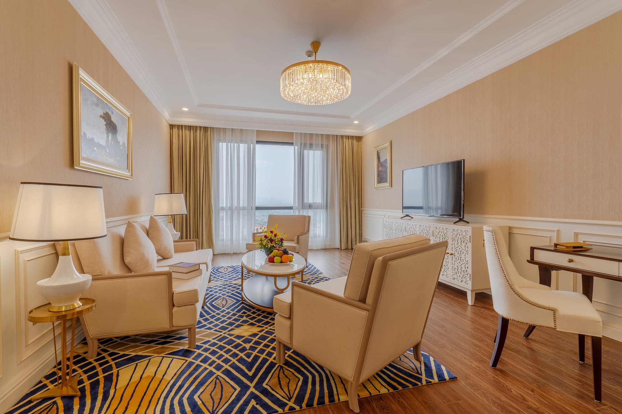Elegant hotel suite living room with sofa, armchairs, and bright window view.
