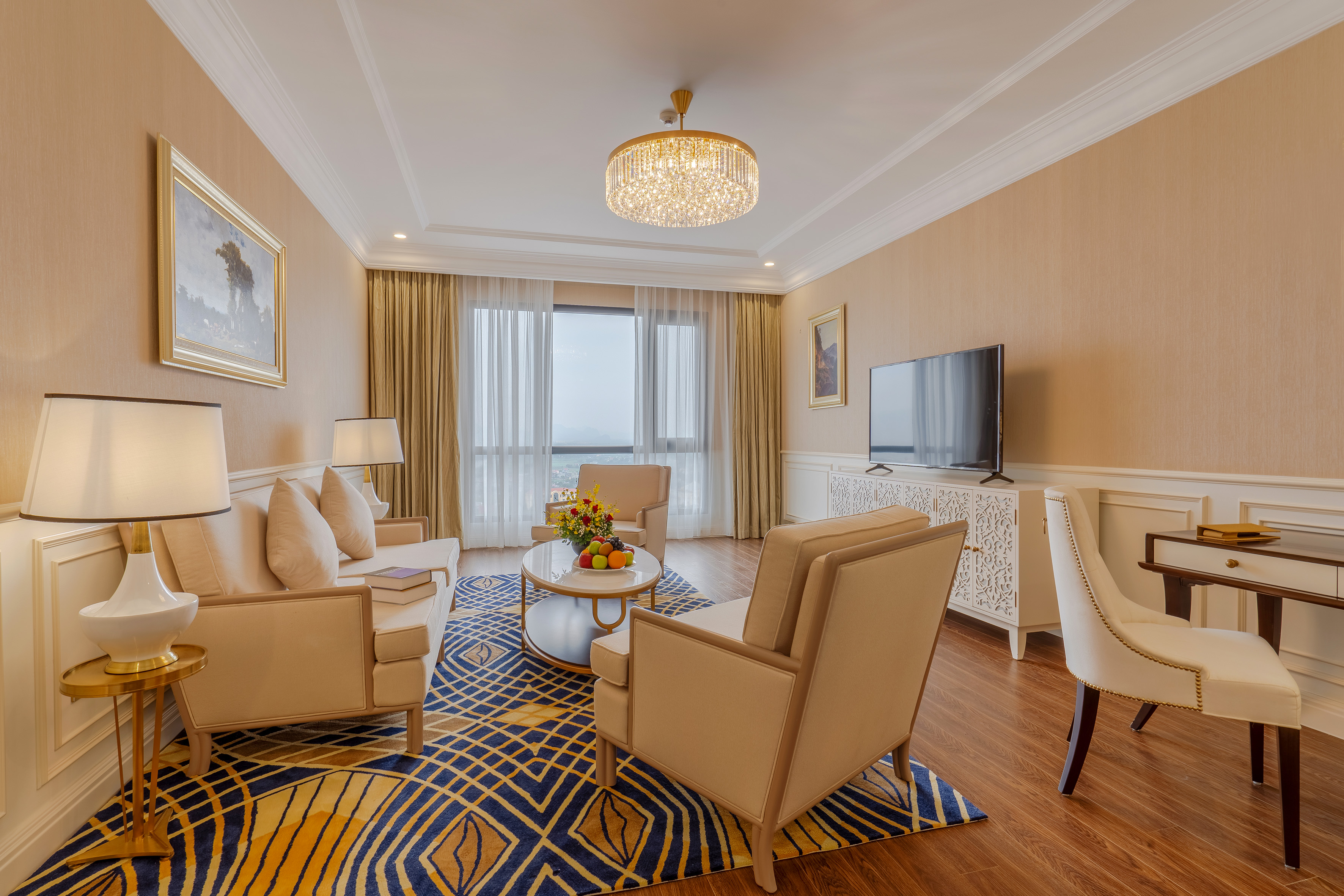 Elegant hotel suite living room with sofa, armchairs, and bright window view.