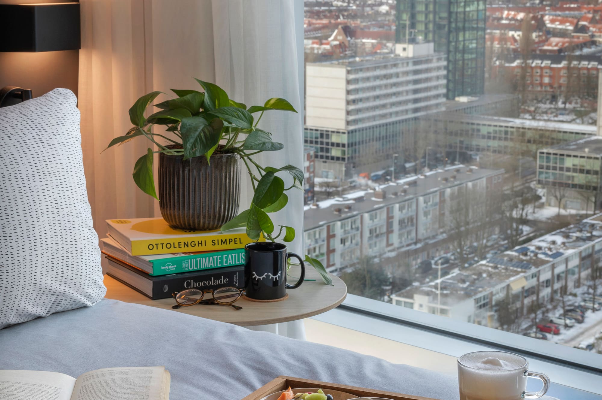 a breakfast in bed with a window overlooking a city