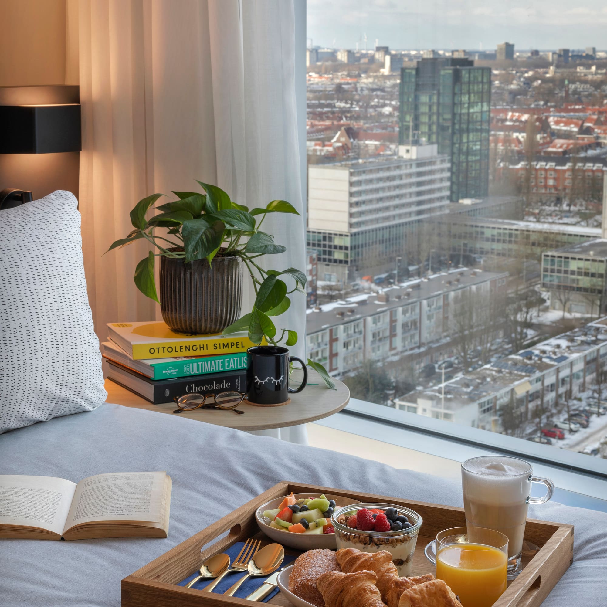 a breakfast in bed with a window overlooking a city
