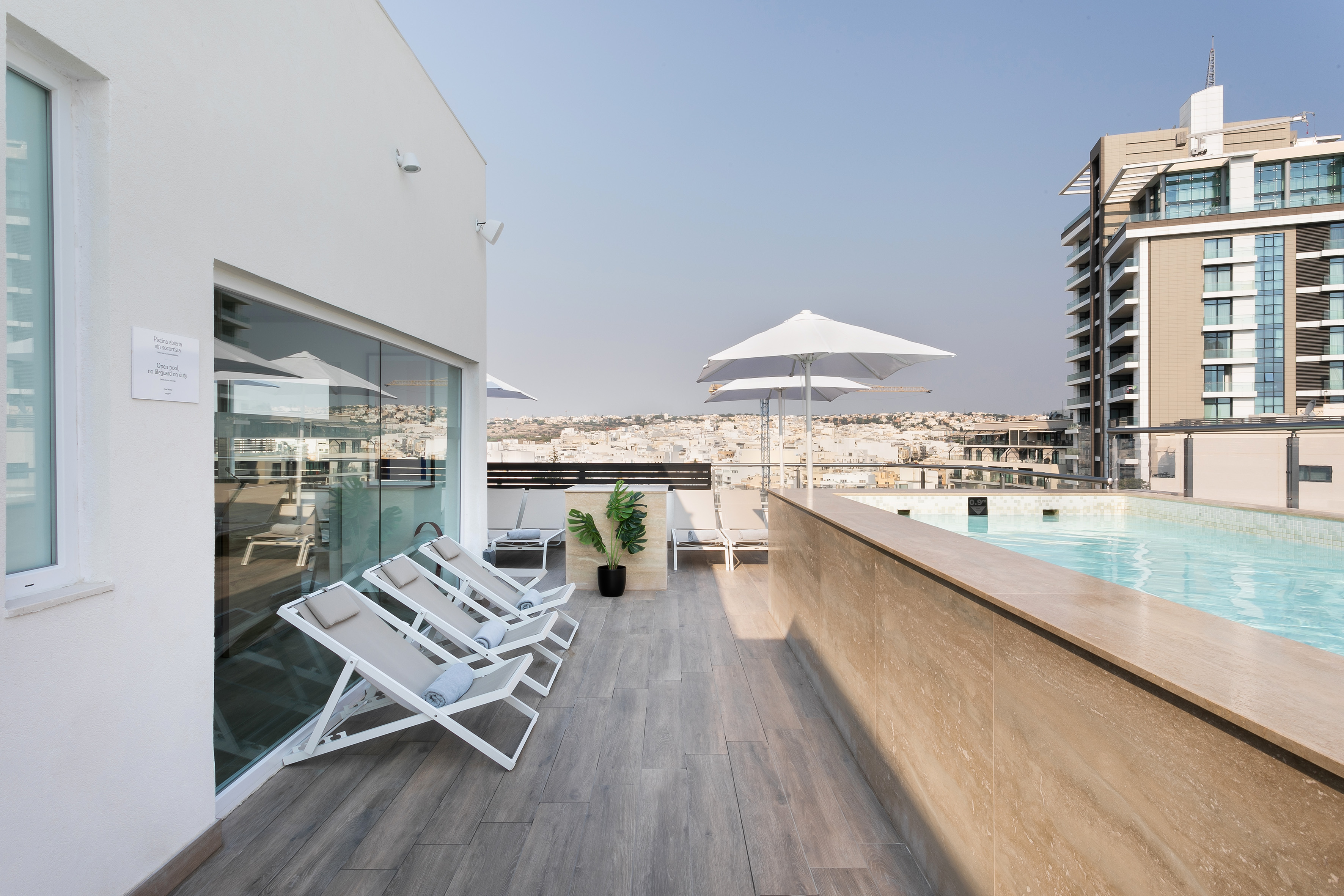 a pool with chairs and umbrellas on a rooftop