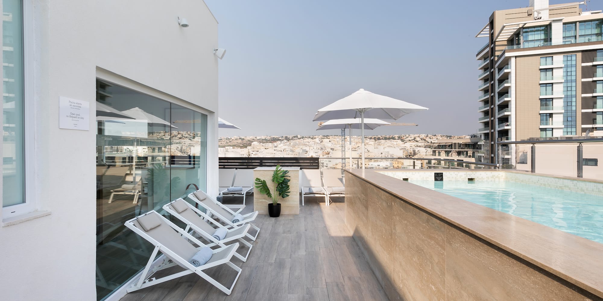 a pool with chairs and umbrellas on a rooftop