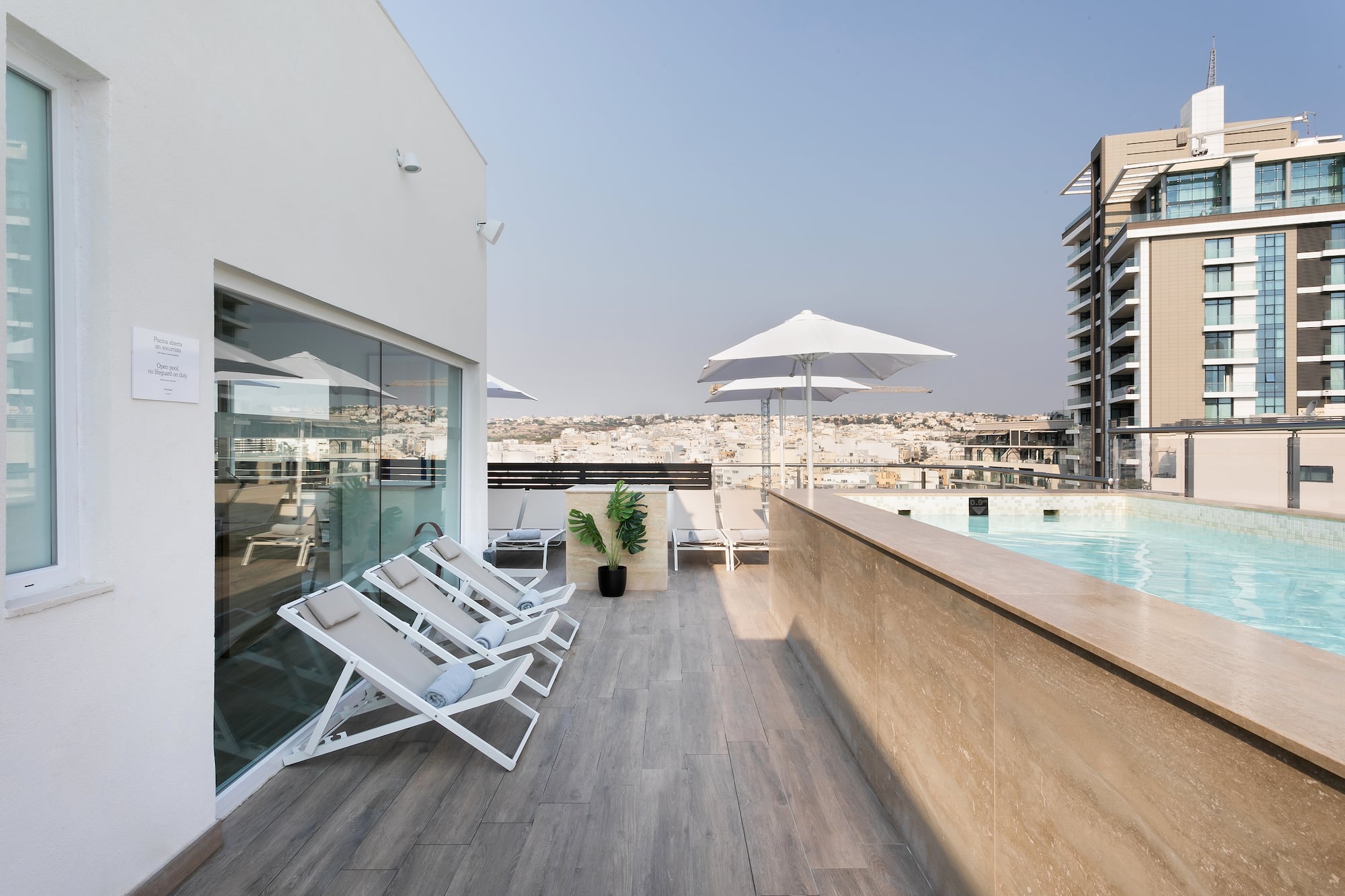 a pool with chairs and umbrellas on a rooftop