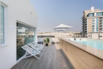 a pool with chairs and umbrellas on a rooftop