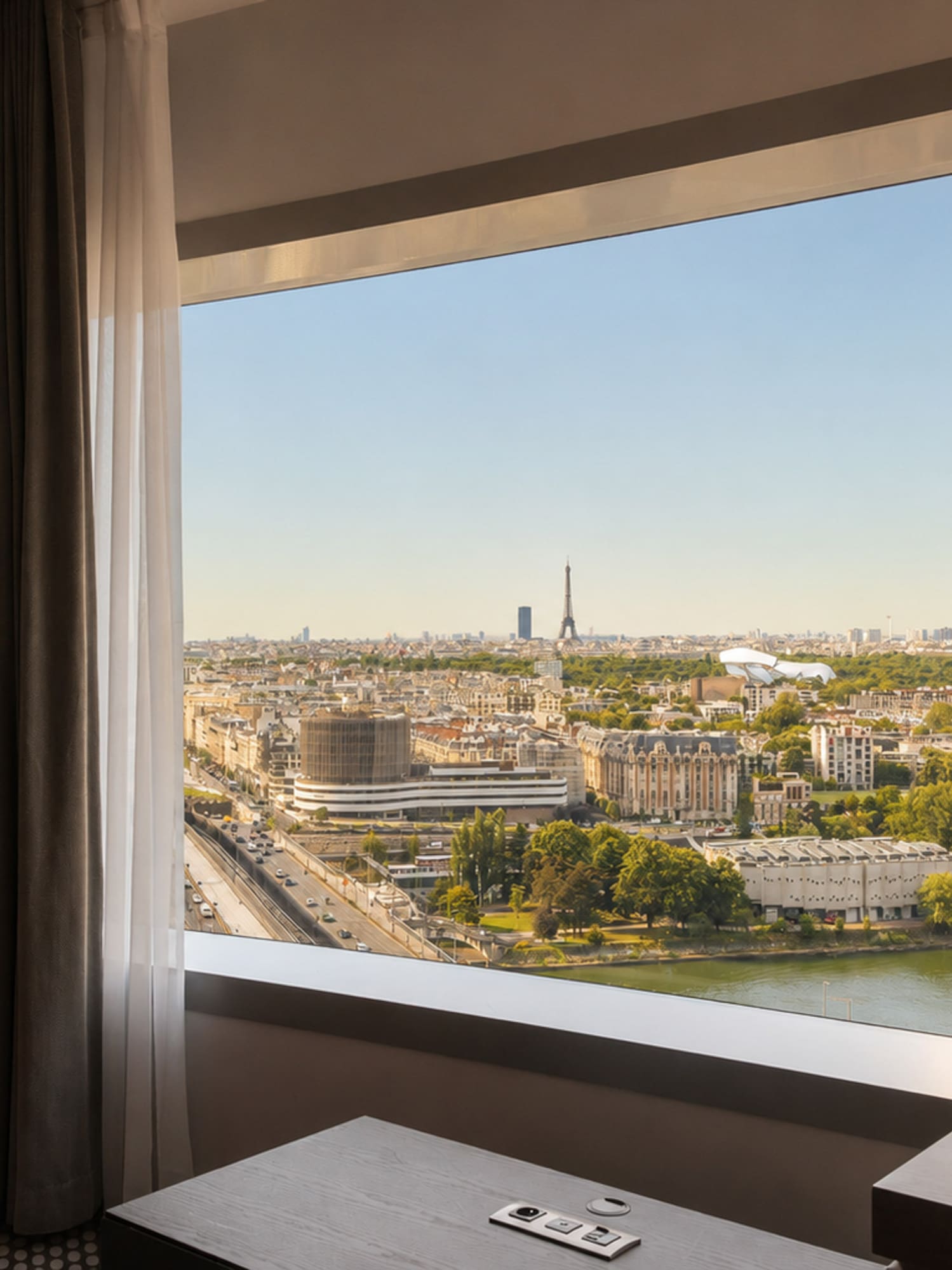 Hotel room with panoramic Paris view, Eiffel Tower, and Seine River.
