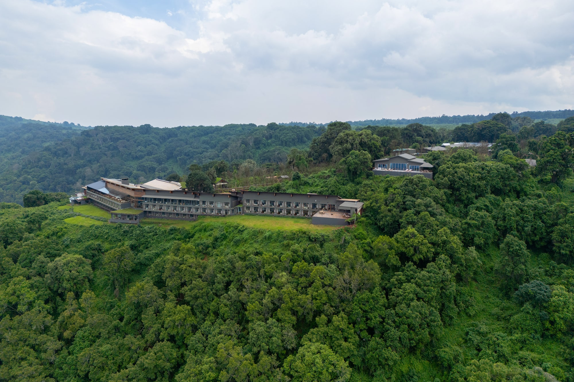 Aerial view of modern forest hotel nestled in vast green landscape.